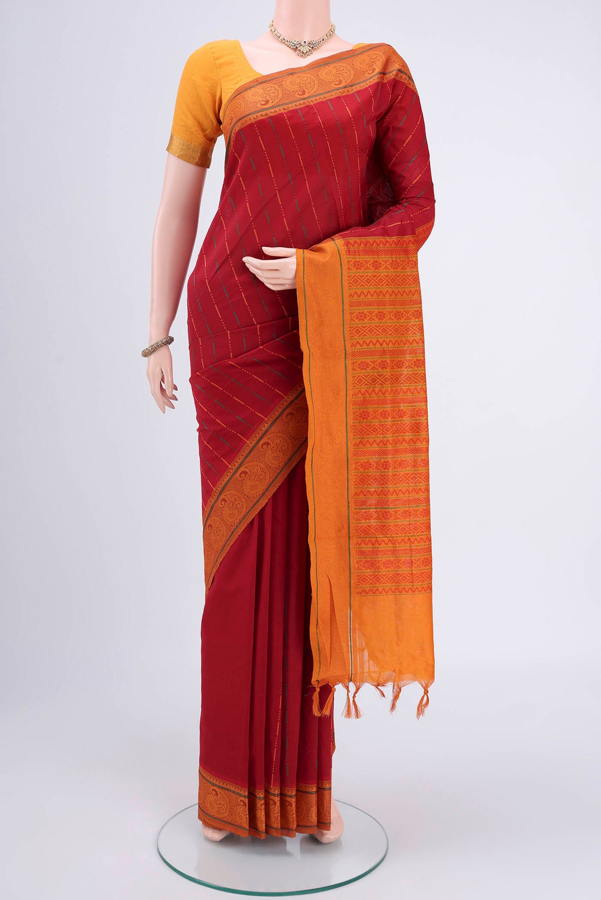 Red Blended Poly Cotton Saree with Stripes on the body and Thread Border.  displayed on a mannequin