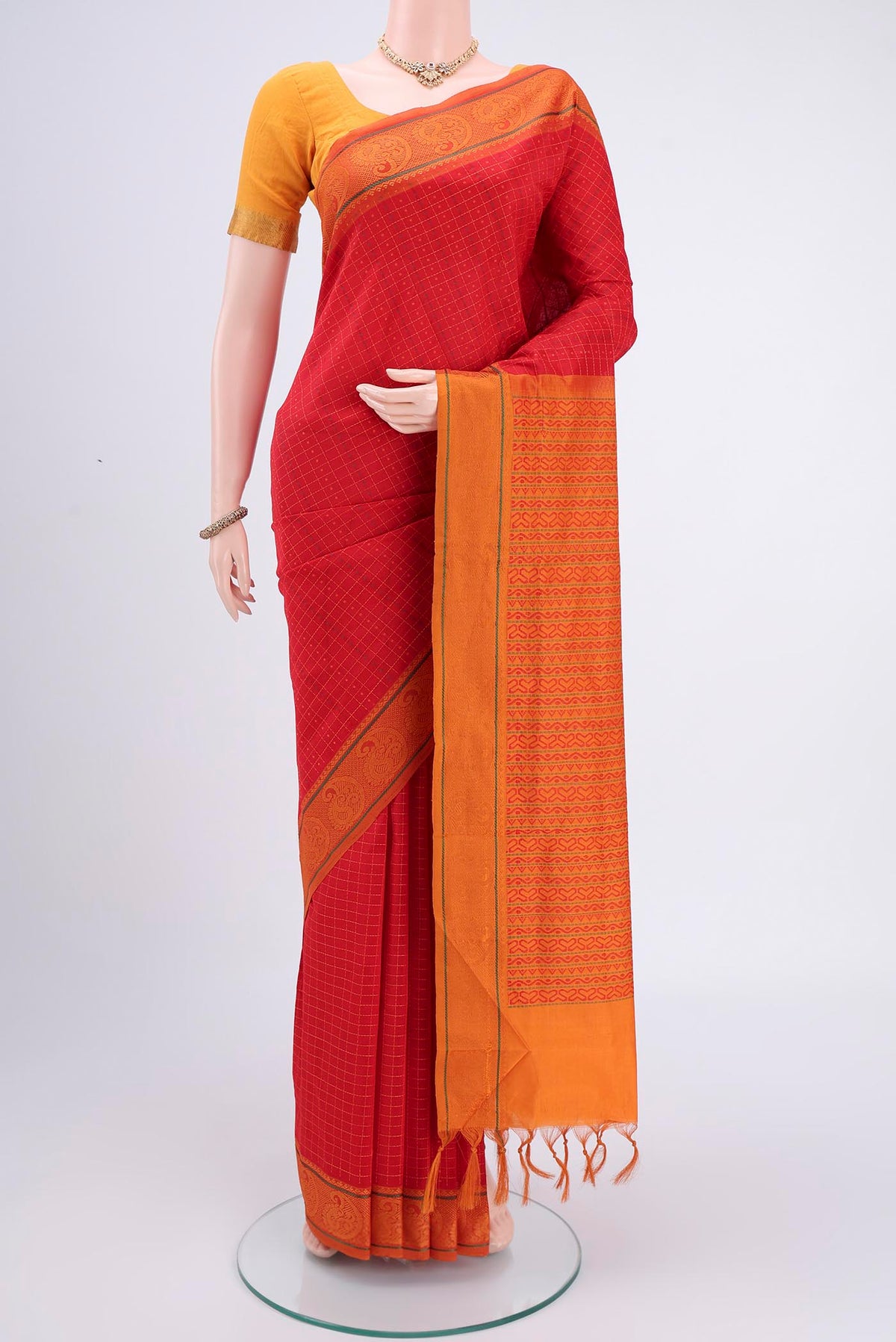 Red Blended Poly Cotton Saree with Checked design on the body and Thread Border.  displayed on a mannequin