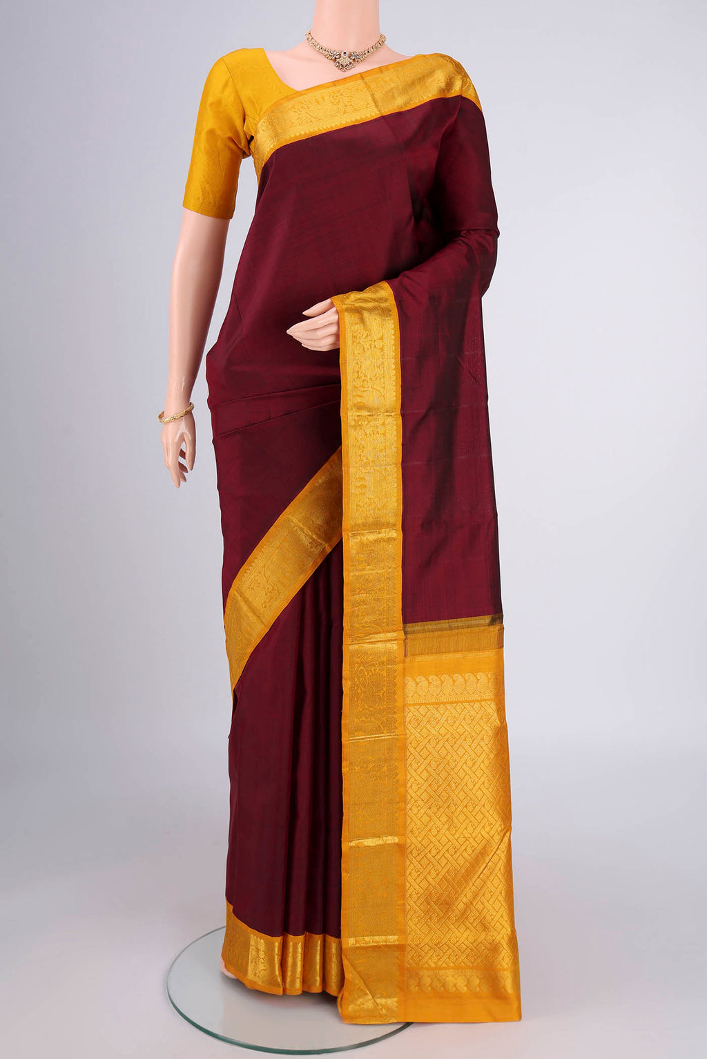 Maroon Kanjivaram Silk Saree with Plain Body and Zari Border.  displayed on a mannequin