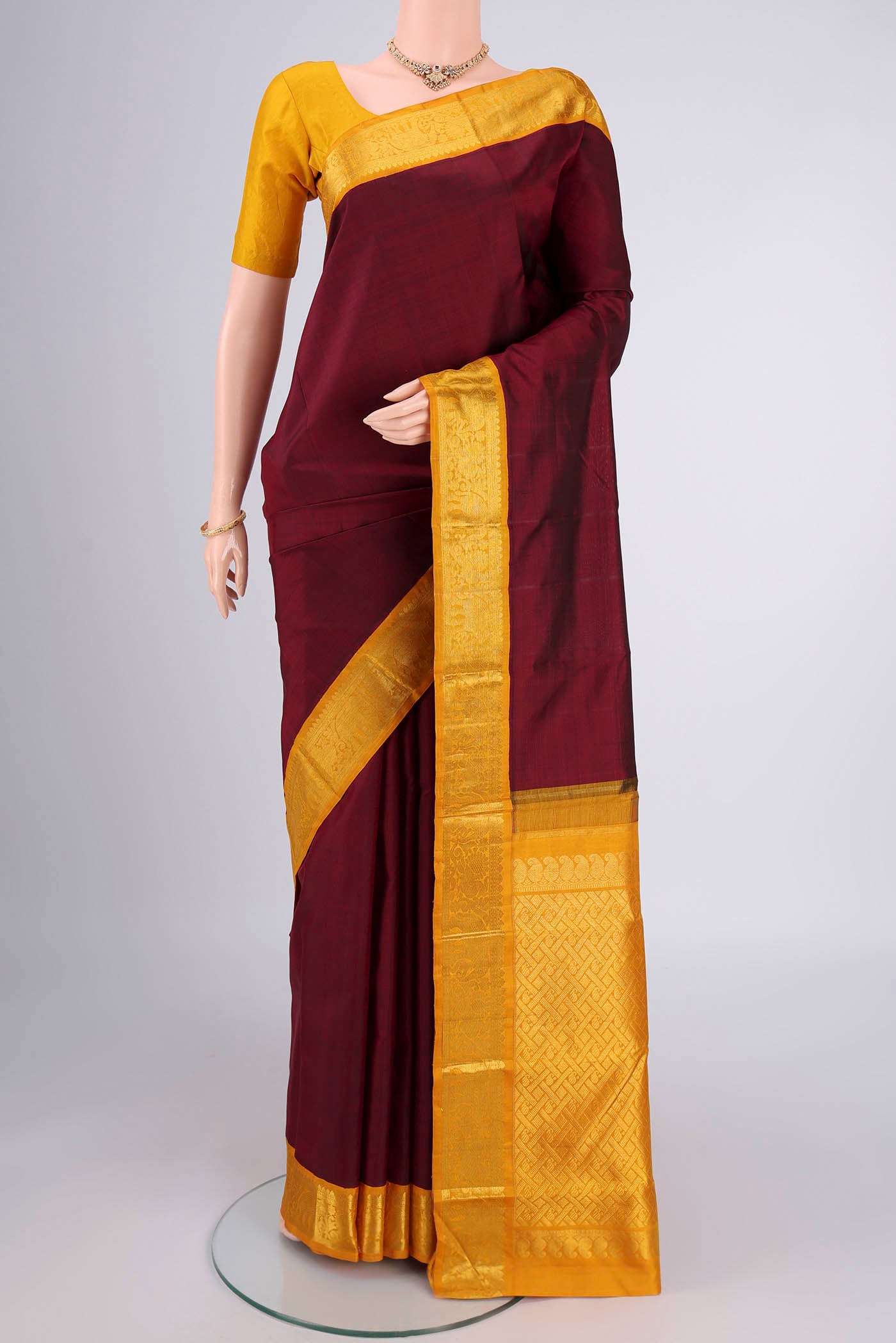 Maroon Kanjivaram Silk Saree with Plain Body and Zari Border.  displayed on a mannequin