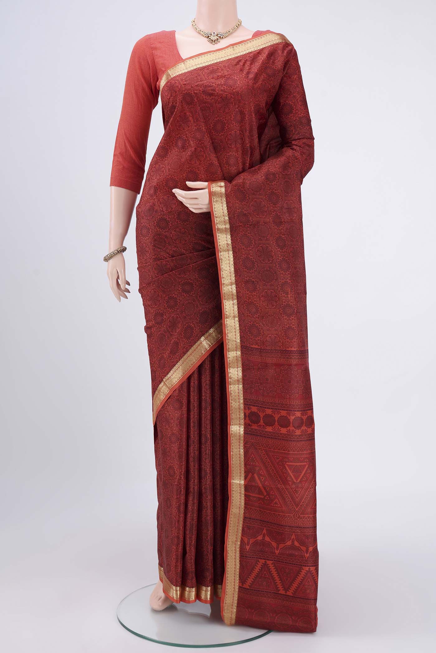 Brick Orange Printed Silk Saree with Printed design on the body and Zari Border.  displayed on a mannequin
