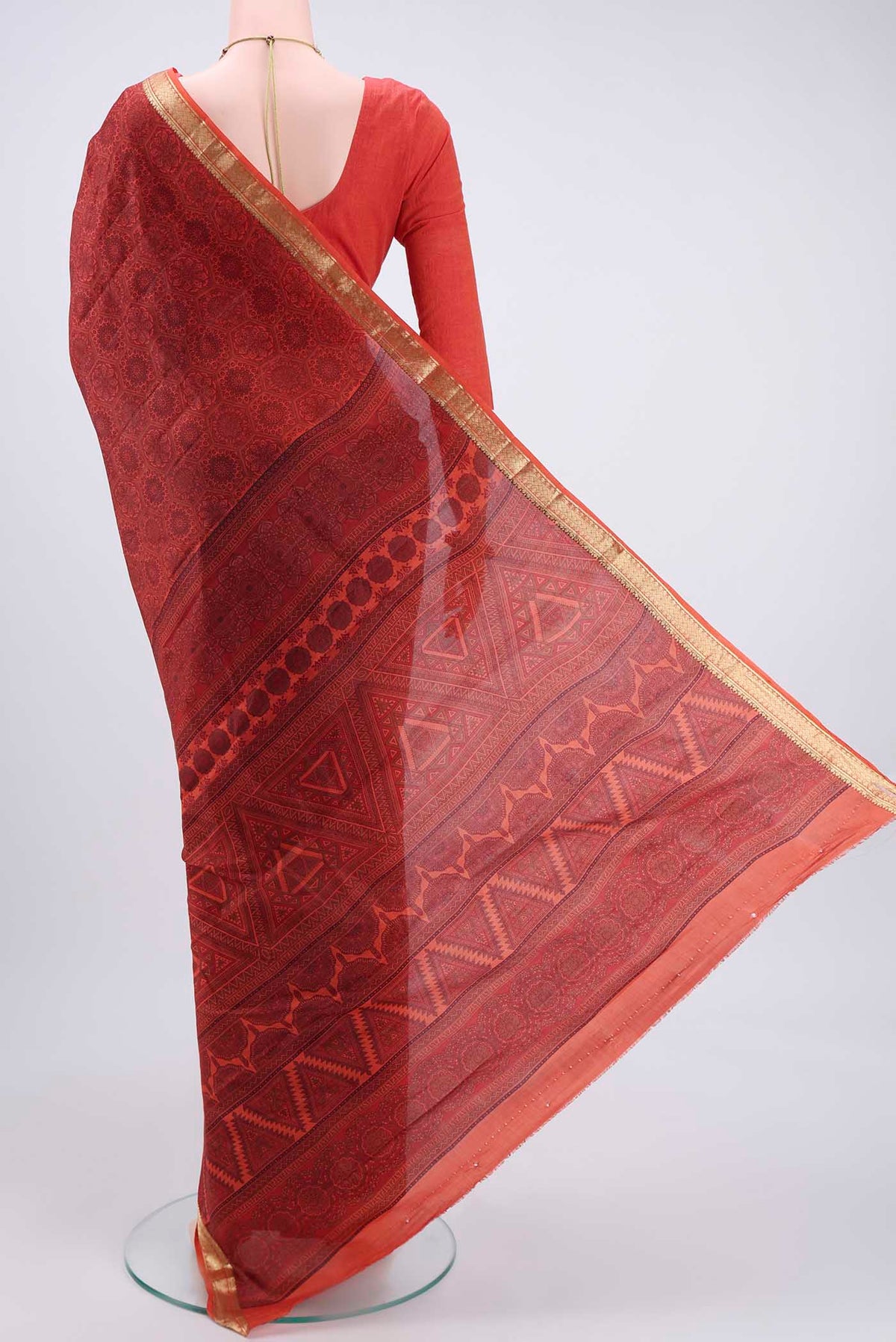 Flat view of Brick Orange Printed Silk Saree with Printed design on the body and Zari Border. 