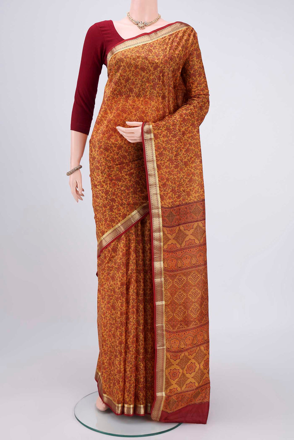 Mustard Printed Silk Saree with Printed design on the body and Zari Border.  displayed on a mannequin