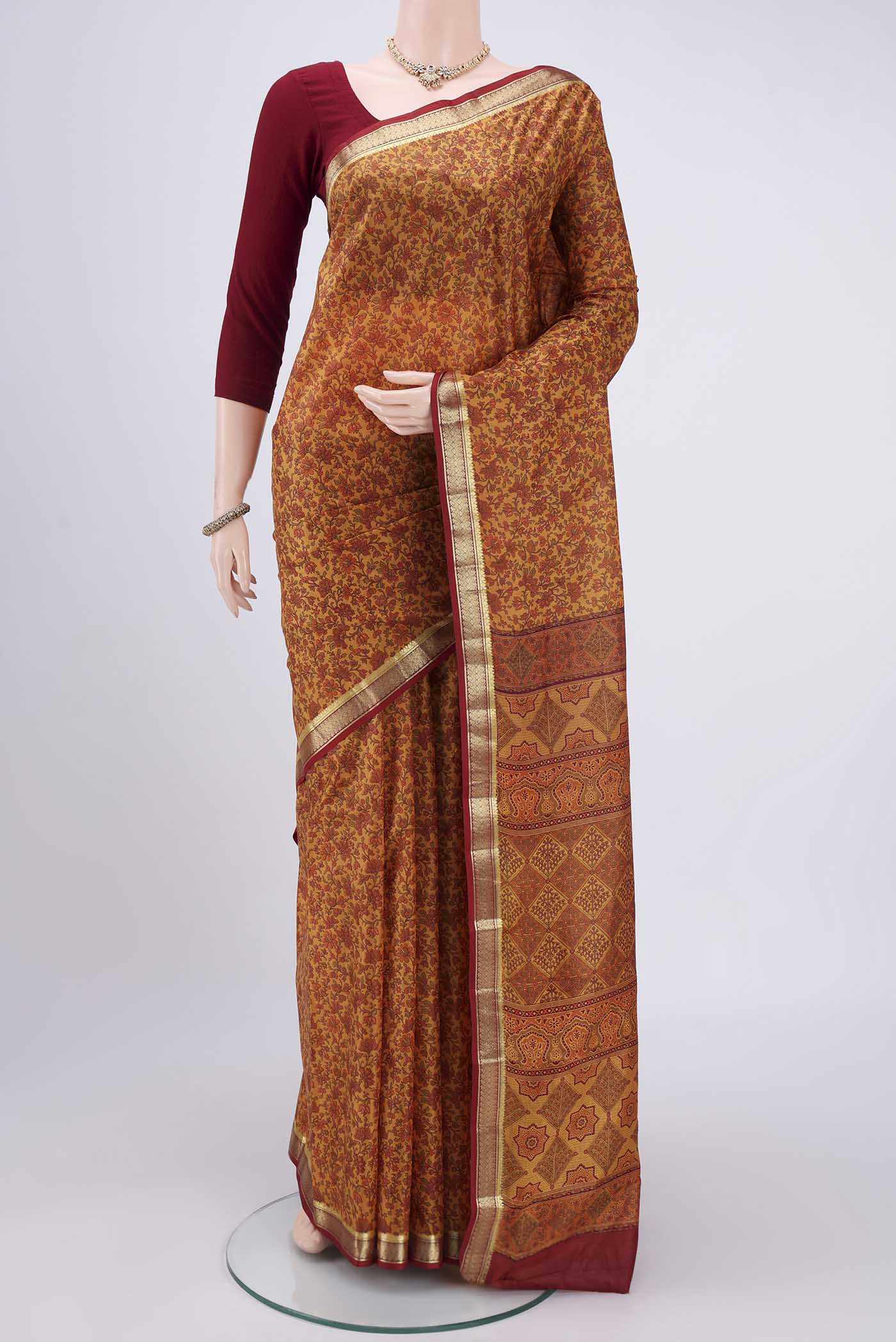 Mustard Printed Silk Saree with Printed design on the body and Zari Border.  displayed on a mannequin