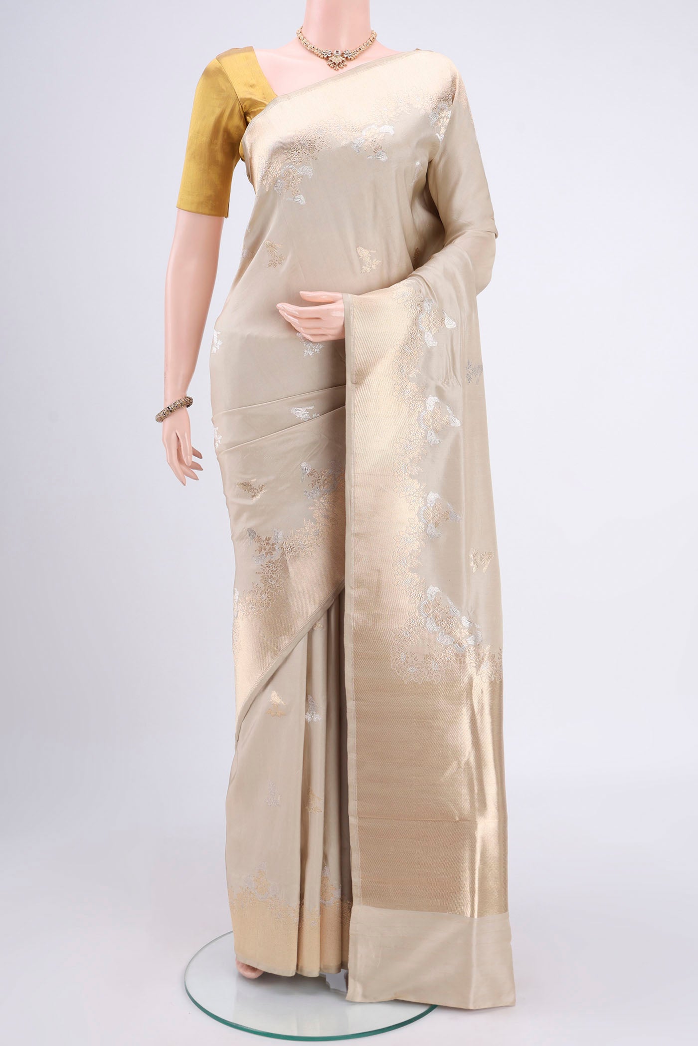 Beige Banarasi Silk Saree with Zari Butta on the body and Zari Border.  displayed on a mannequin
