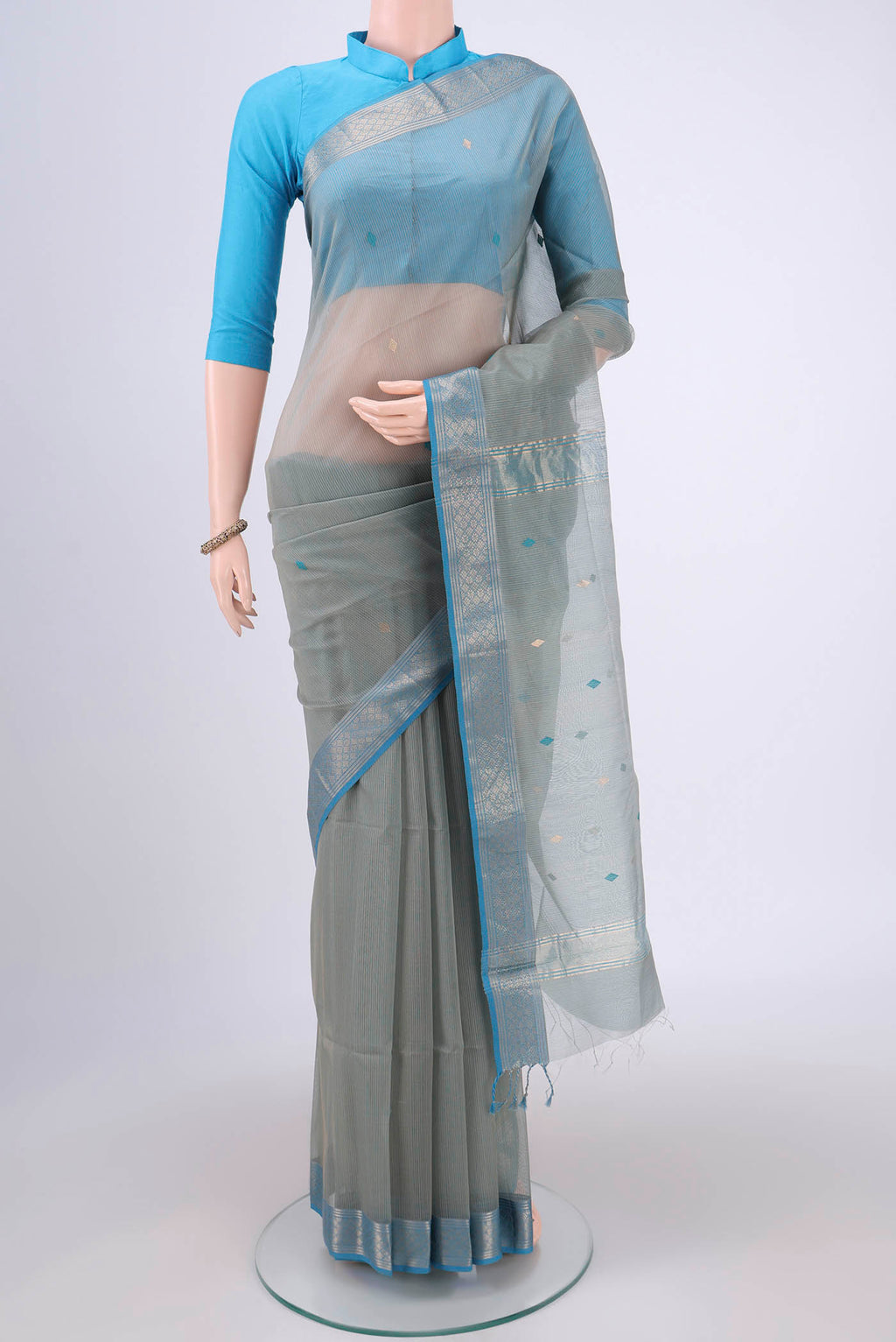 Beige Maheshwari Silk Cotton Saree with Zari And Thread Butta on the body and Zari Border.  displayed on a mannequin