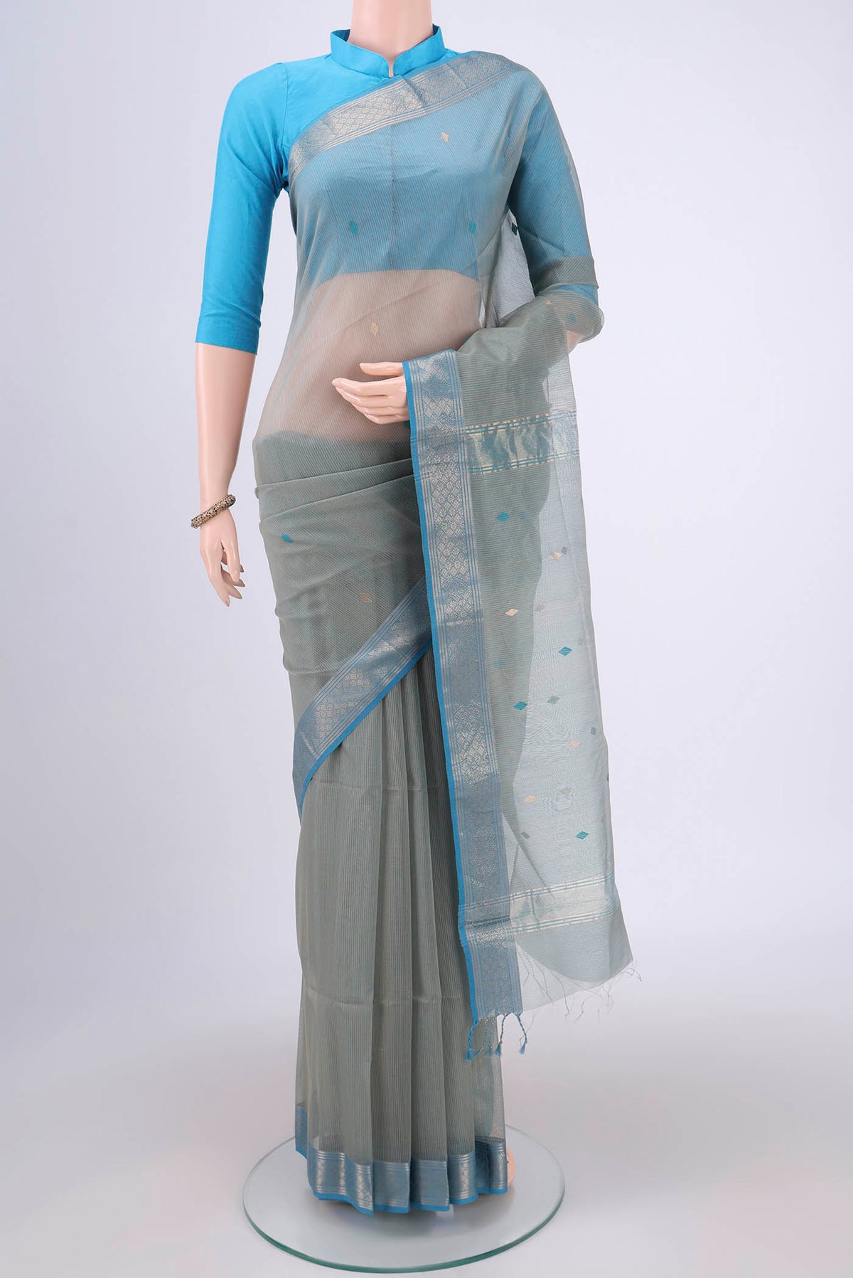 Beige Maheshwari Silk Cotton Saree with Zari And Thread Butta on the body and Zari Border.  displayed on a mannequin