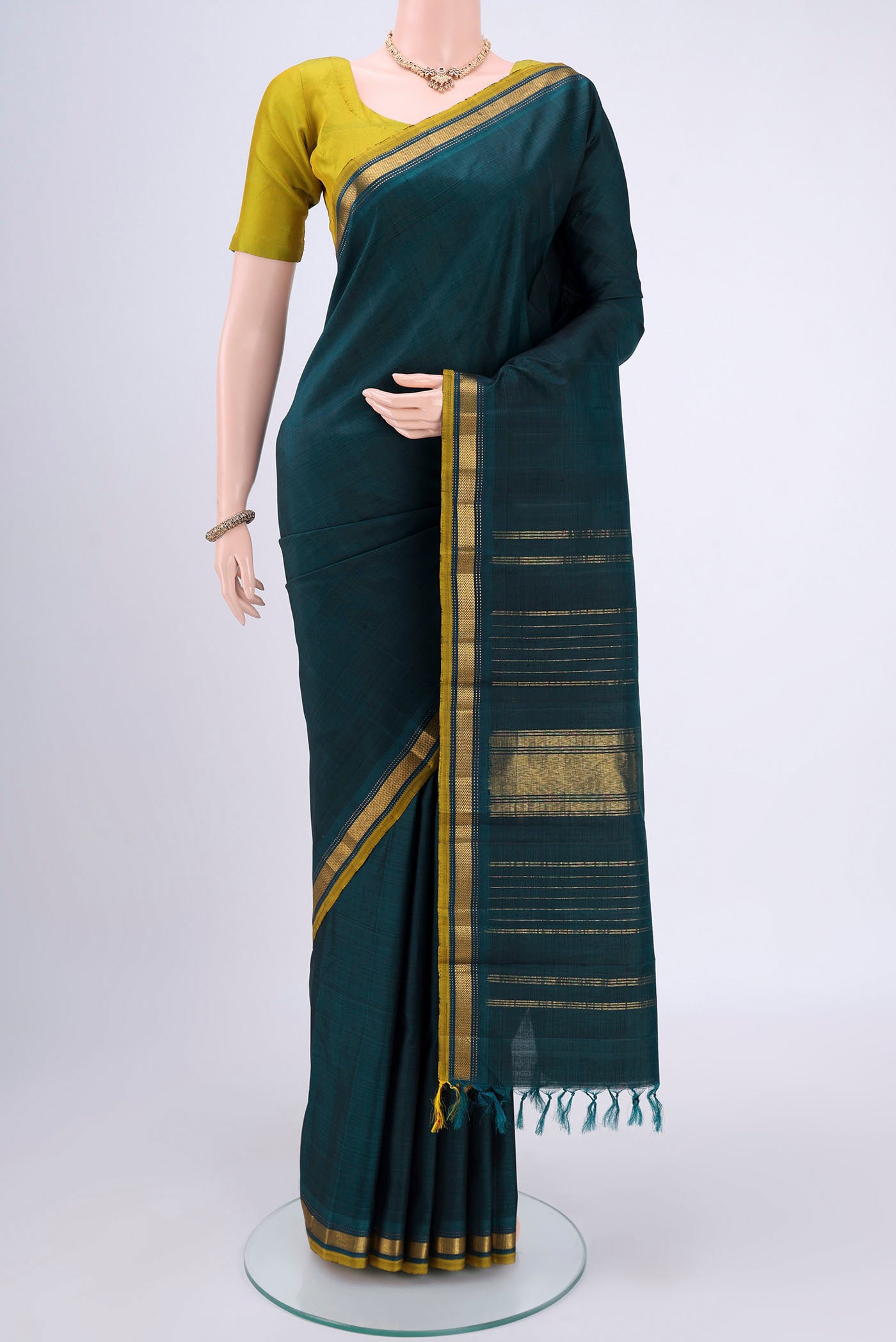 Bottle Green Kanjivaram Silk Saree with Plain Body and Zari Border.  displayed on a mannequin