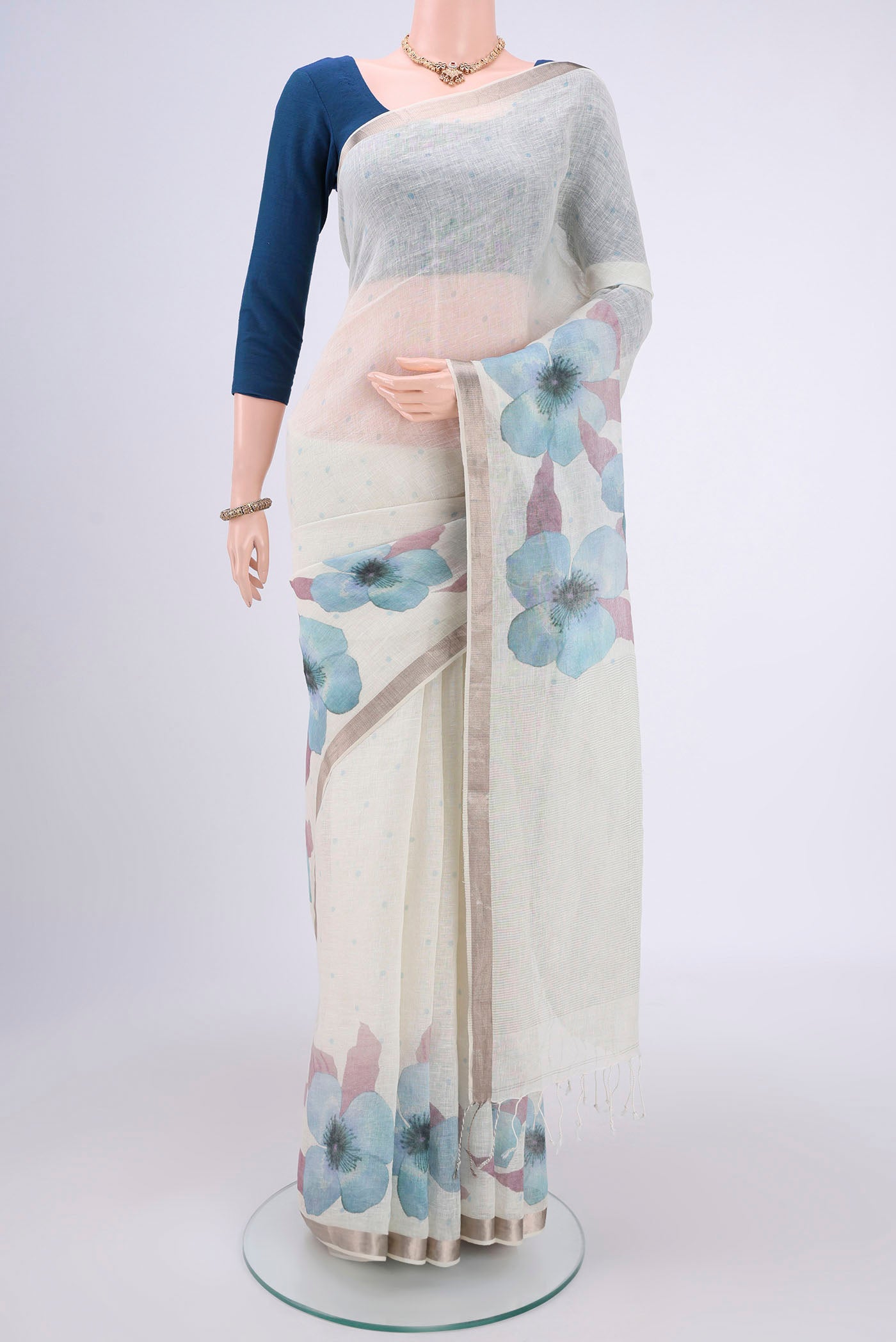 White Linen Saree with Floral Print on the body and Zari Border.  displayed on a mannequin