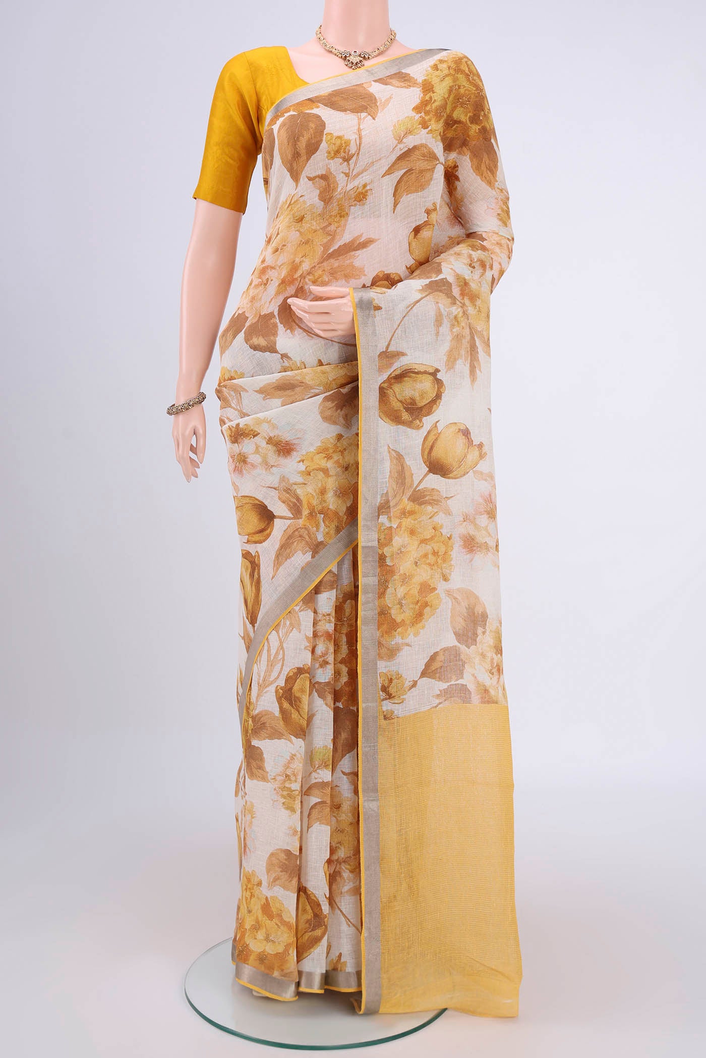 Beige Linen Saree with Floral Print on the body and Zari Border.  displayed on a mannequin