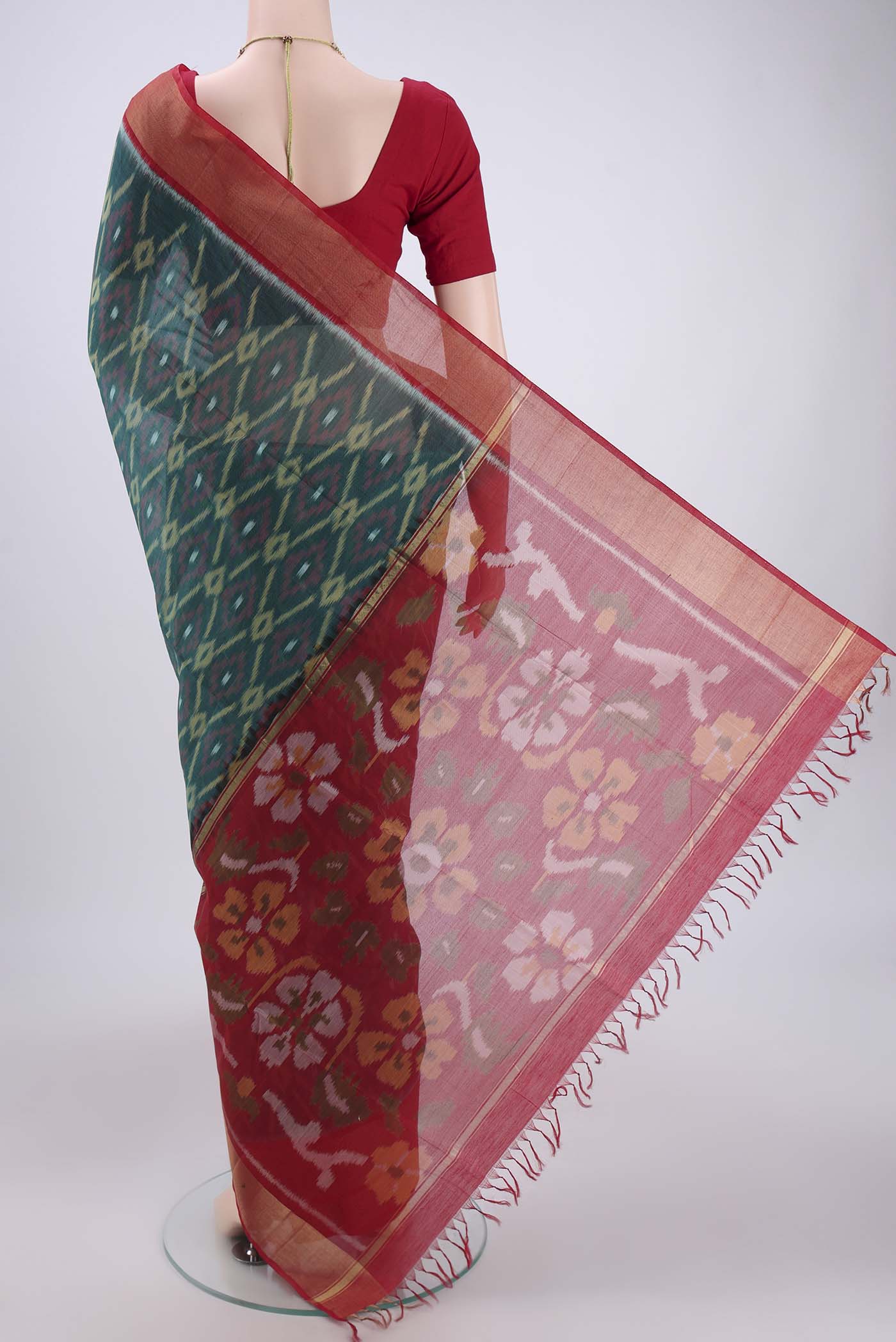 Flat view of Green Silk Cotton Saree with Ikat design on the body and Zari Border. 