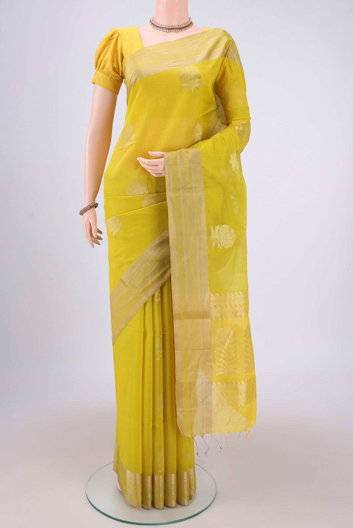 Lemon Yellow Silk Cotton Saree with Zari Butta on the body and Zari Border.  displayed on a mannequin
