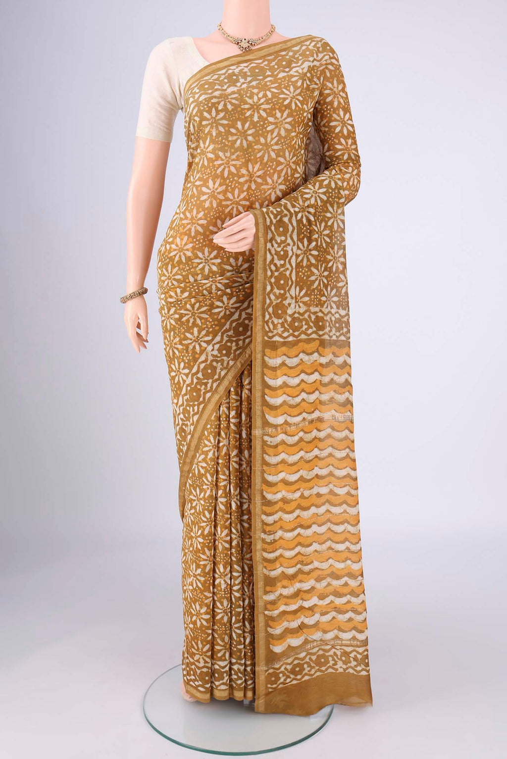 Mustard Maheshwari Silk Cotton Saree with Batik Print on the body and Zari Border.  displayed on a mannequin
