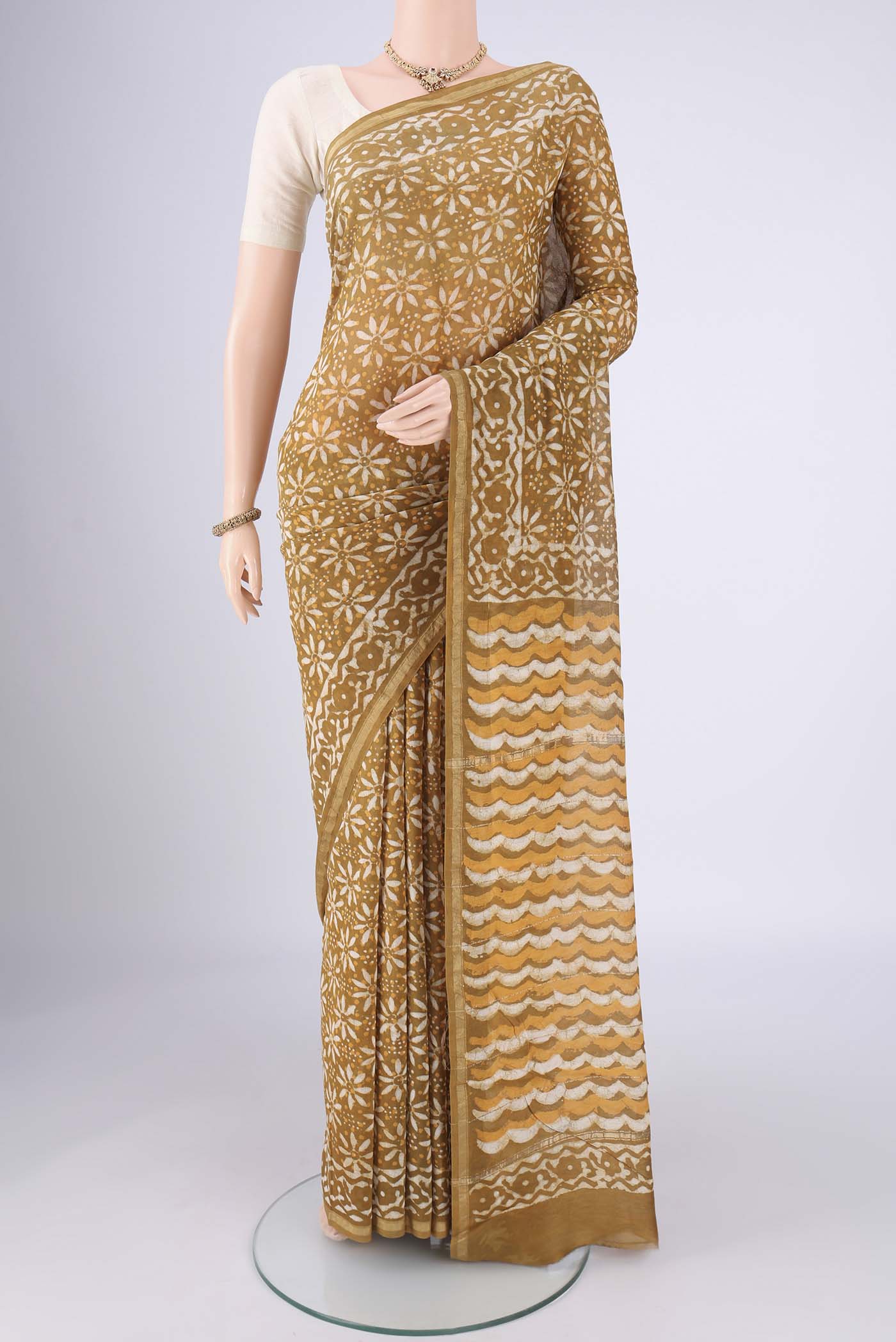 Mustard Maheshwari Silk Cotton Saree with Batik Print on the body and Zari Border.  displayed on a mannequin