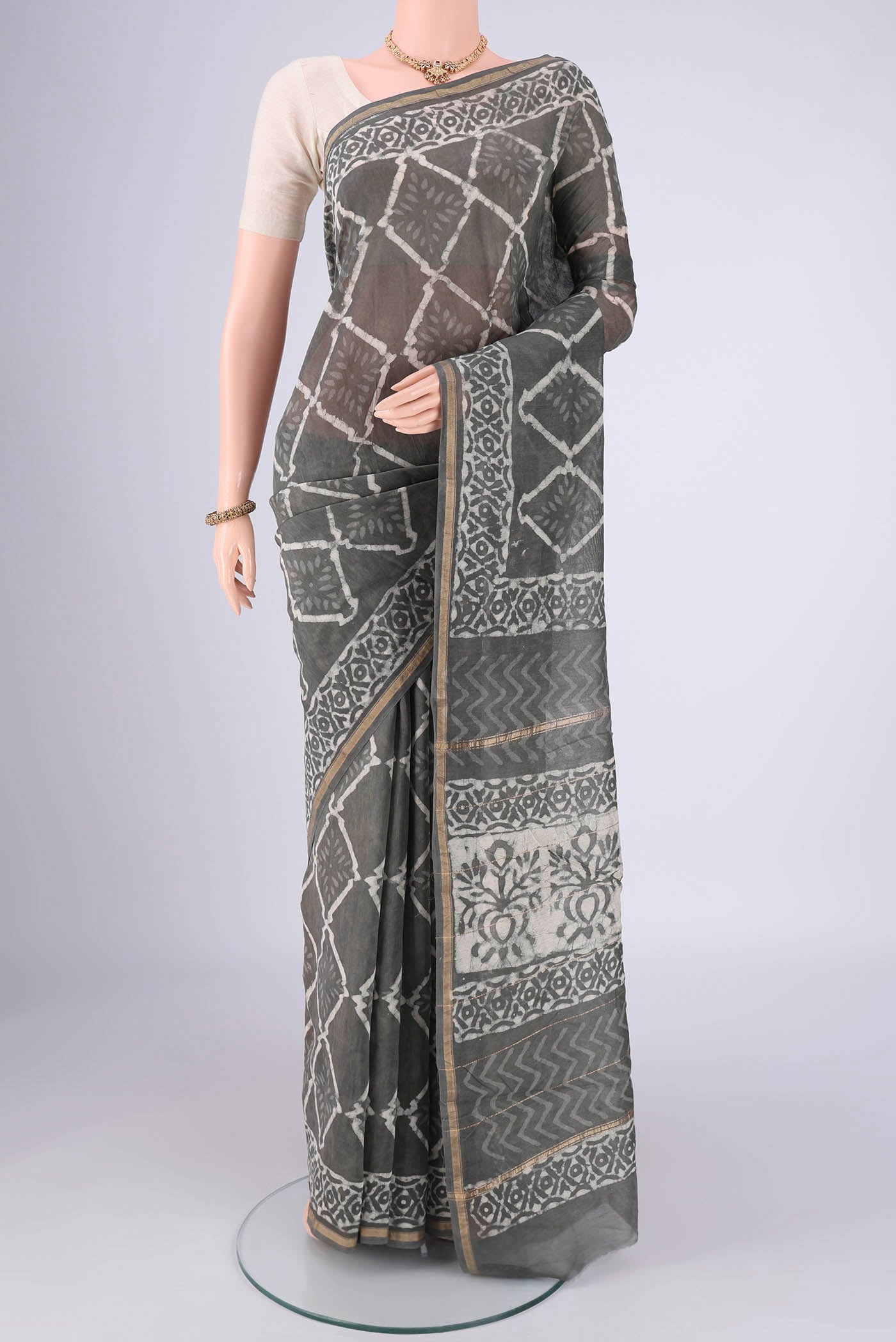Grey Maheshwari Silk Cotton Saree with Batik Print on the body and Zari Border.  displayed on a mannequin