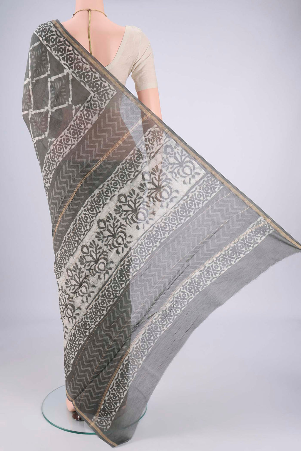 Flat view of Grey Maheshwari Silk Cotton Saree with Batik Print on the body and Zari Border. 