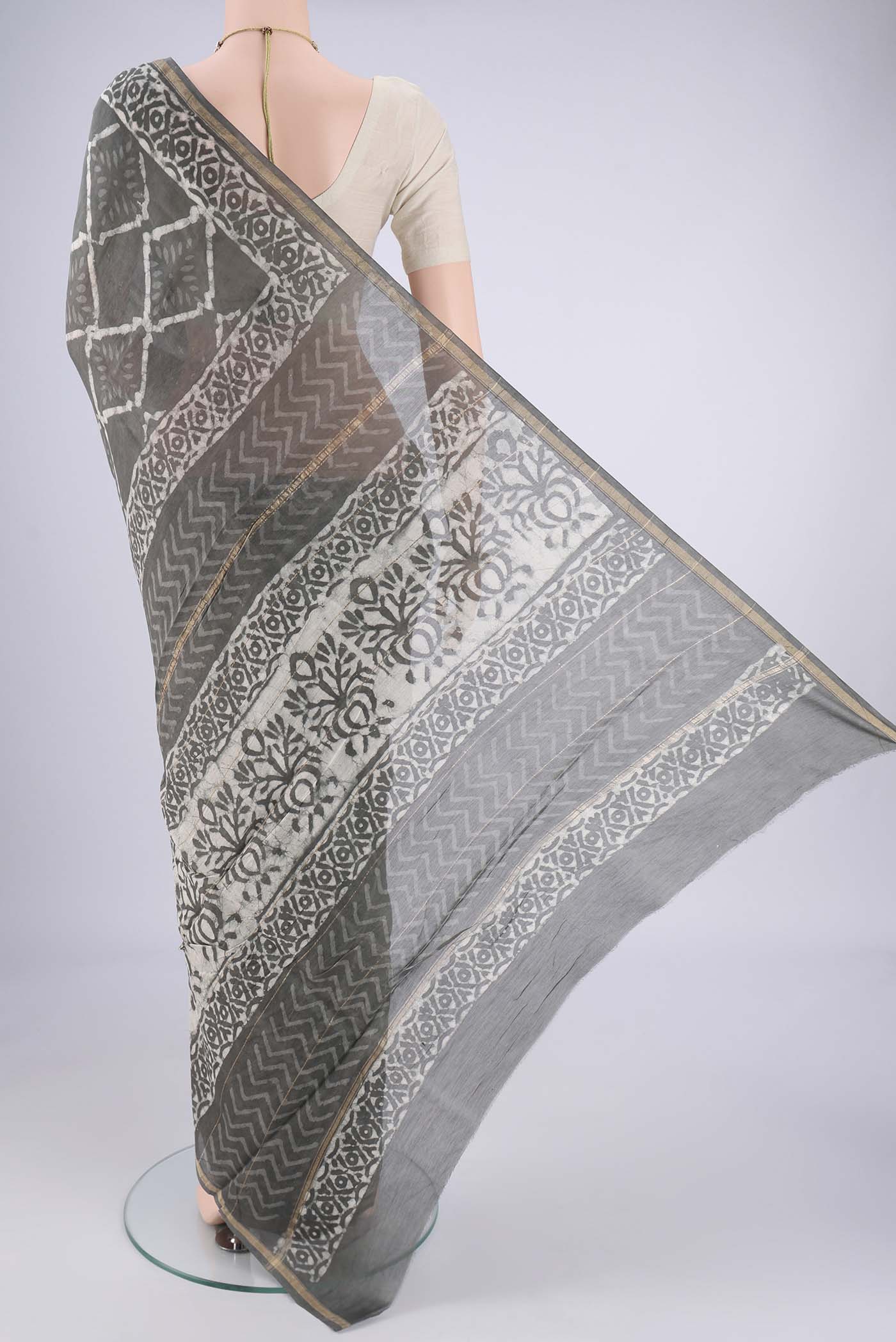 Flat view of Grey Maheshwari Silk Cotton Saree with Batik Print on the body and Zari Border. 