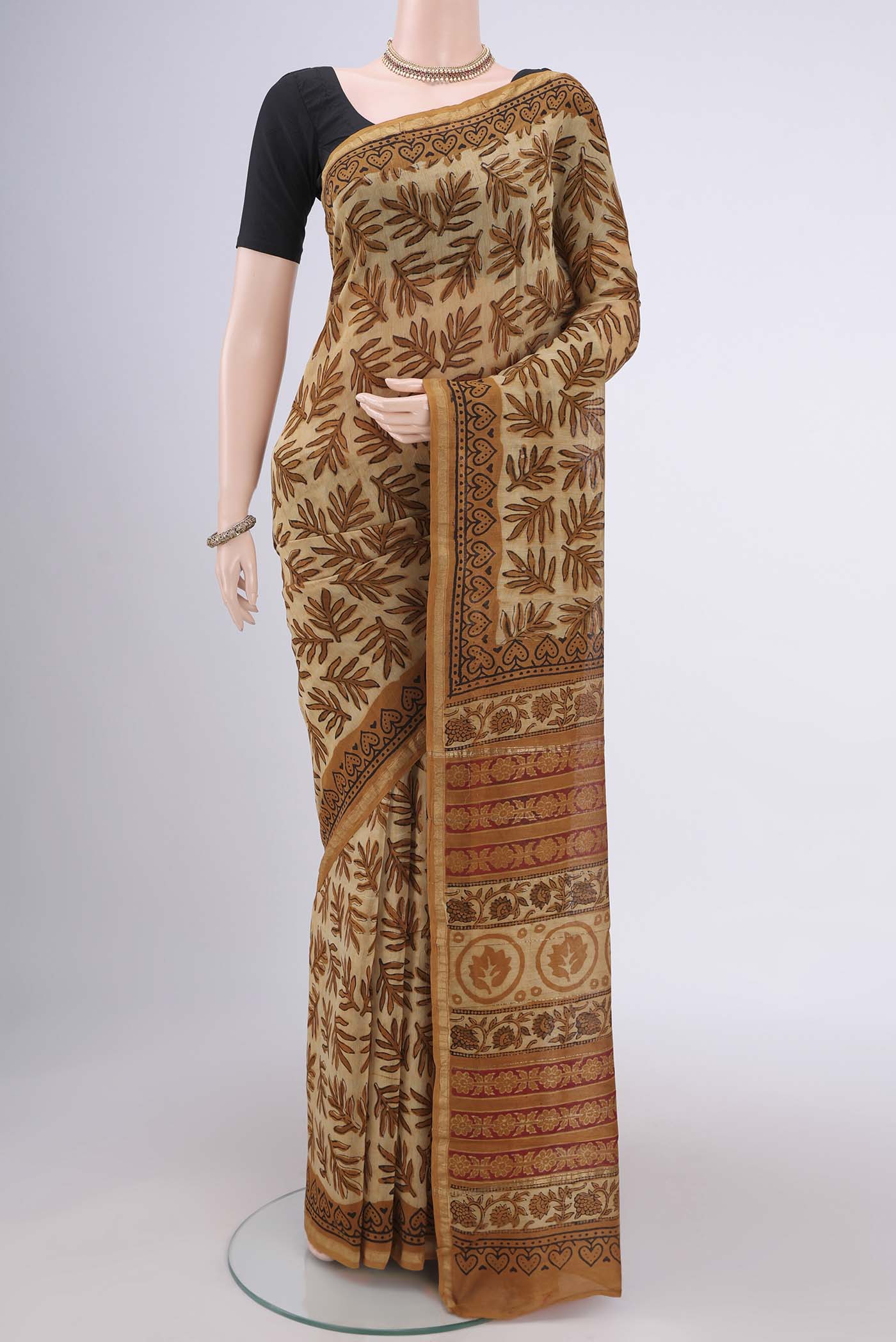 Beige Maheshwari Silk Cotton Saree with Batik Print on the body and Zari Border.  displayed on a mannequin