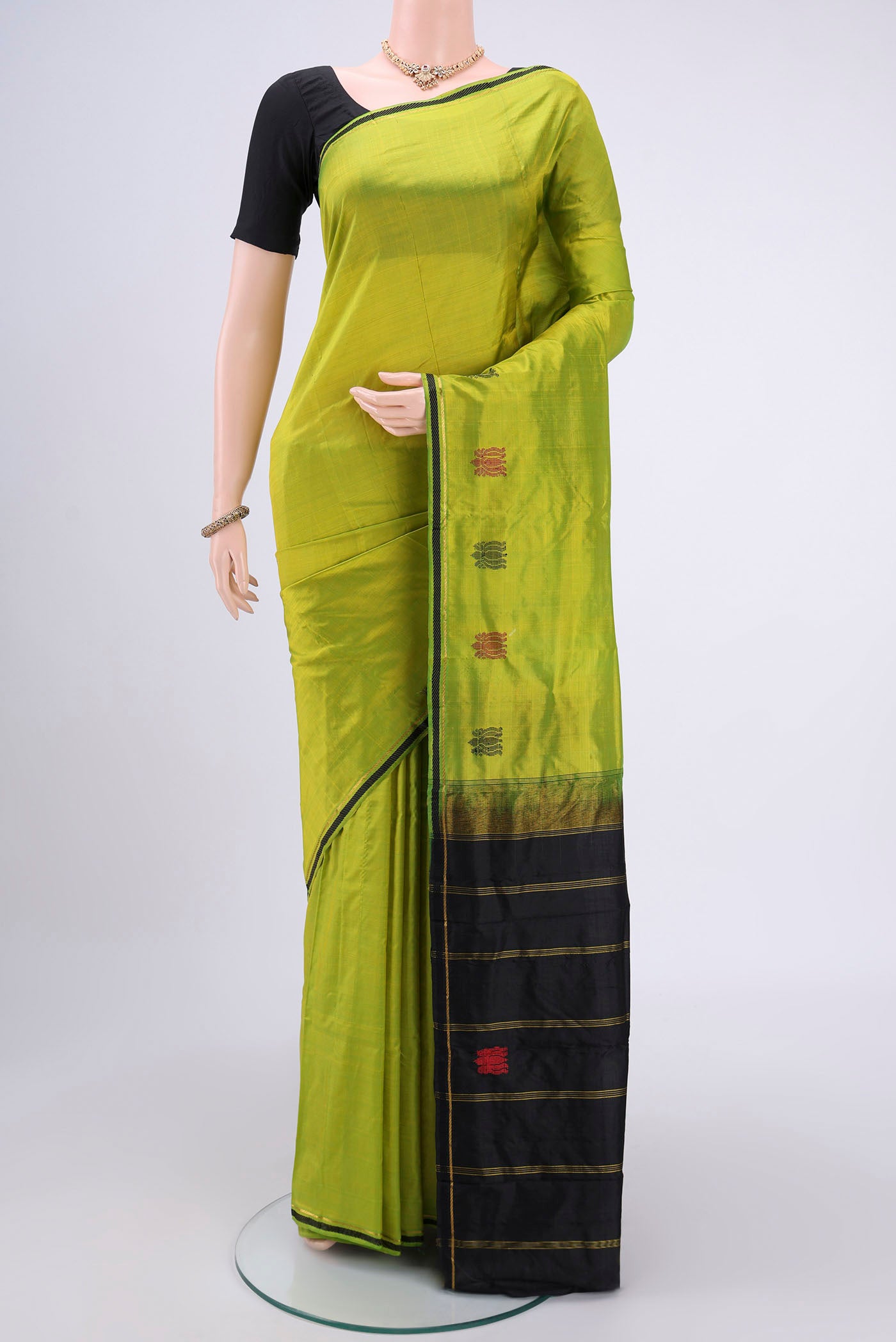 Parrot Green Kanchipuram Silk Saree with Plain Body and Thin Zari Line.  displayed on a mannequin