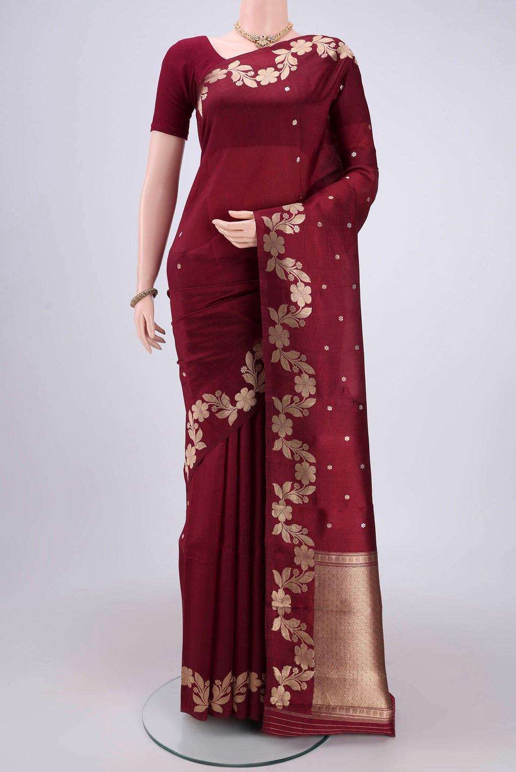 Maroon Banarasi Katan Silk Saree with Zari Butta on the body and Zari Border.  displayed on a mannequin