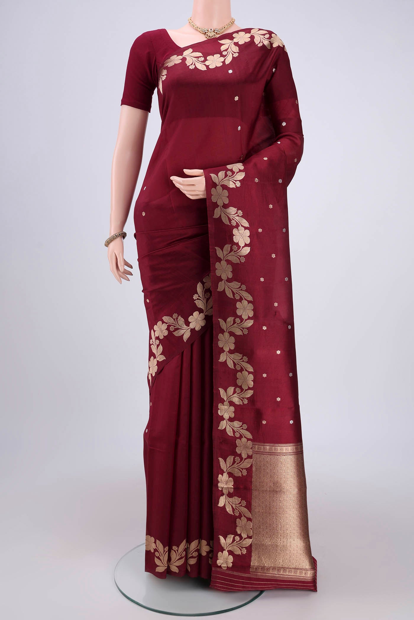 Maroon Banarasi Katan Silk Saree with Zari Butta on the body and Zari Border.  displayed on a mannequin