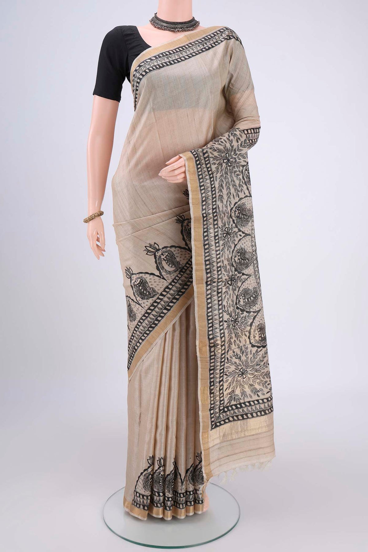Beige Tussar Silk Saree with Printed design on the body and Zari Border.  displayed on a mannequin