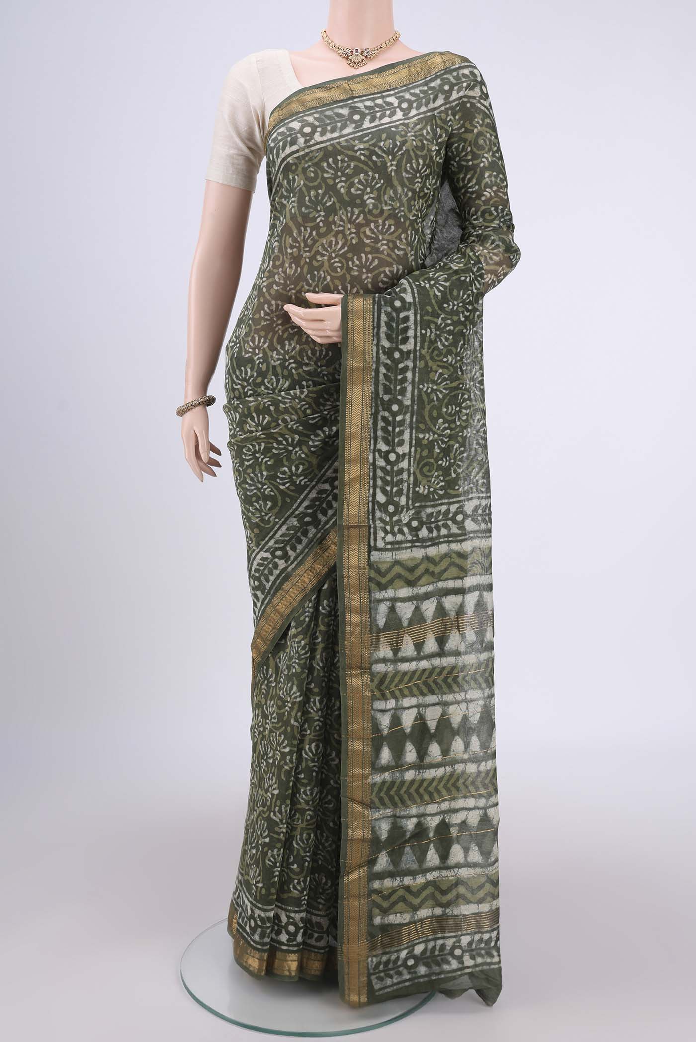 Olive Green Maheshwari Silk Cotton Saree with Batik Print on the body and Zari Border.  displayed on a mannequin