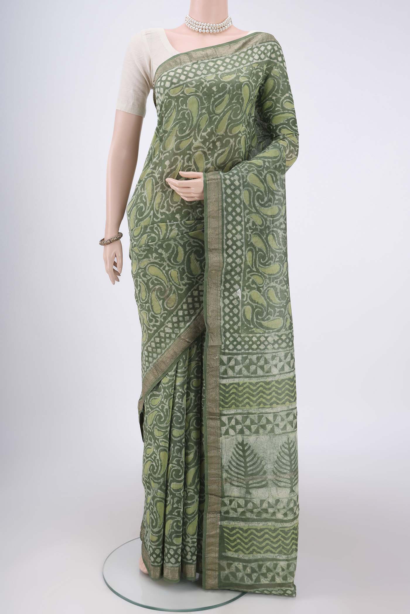 Olive Green Maheshwari Silk Cotton Saree with Batik Print on the body and Zari Border.  displayed on a mannequin