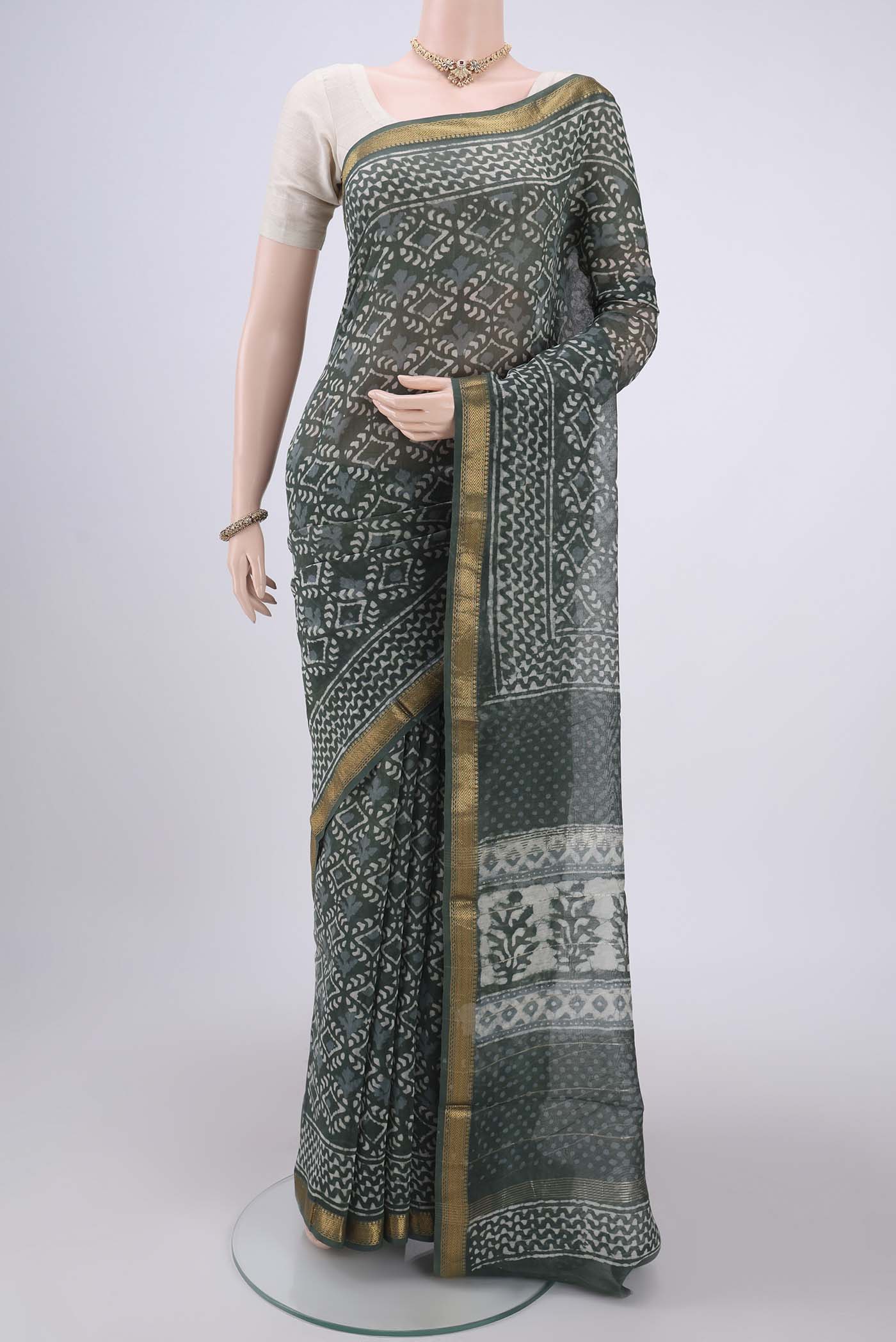 Olive Green Maheshwari Silk Cotton Saree with Batik Print on the body and Zari Border.  displayed on a mannequin