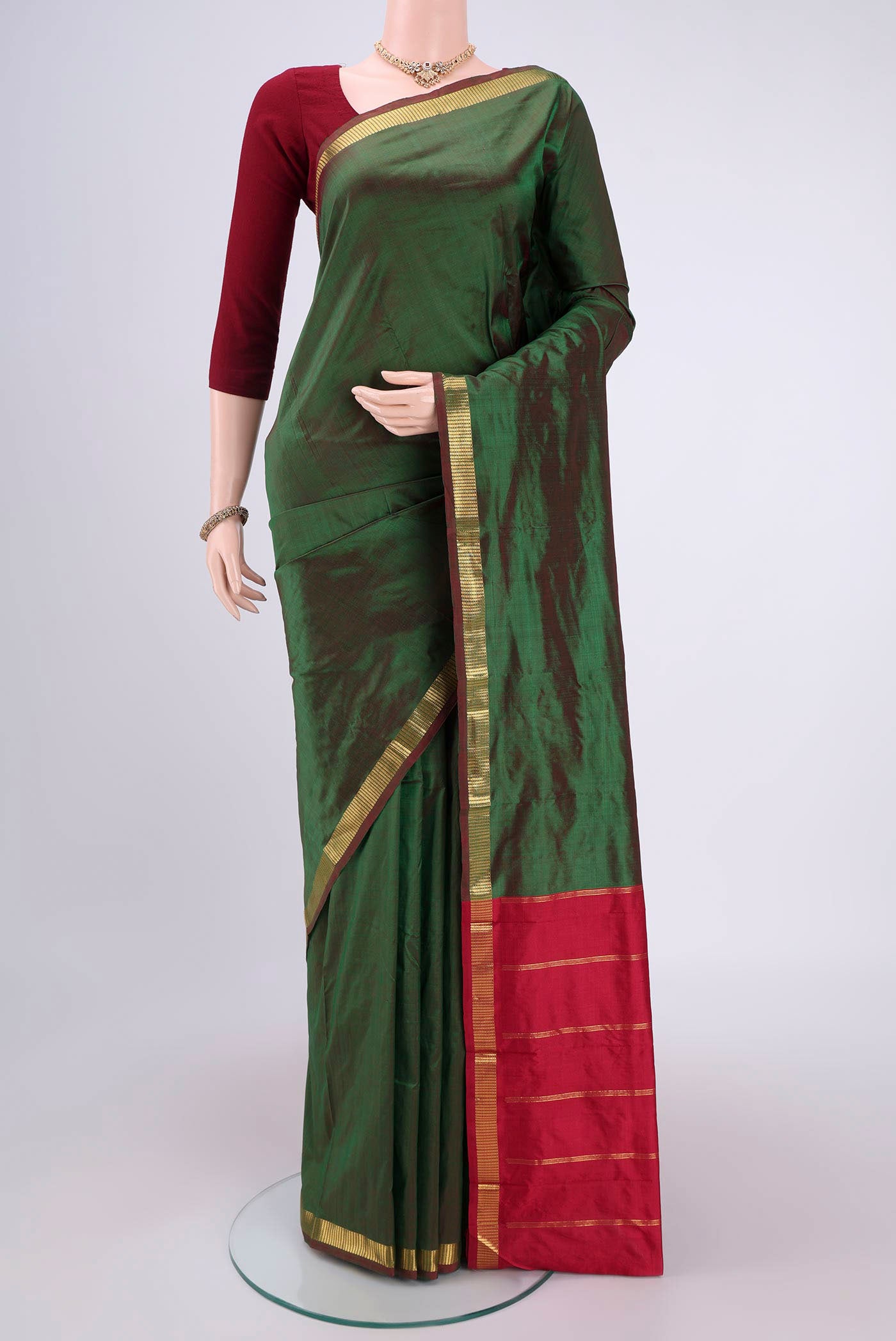 Bottle Green Kanchipuram Silk Saree with Plain Body and Zari Border.  displayed on a mannequin