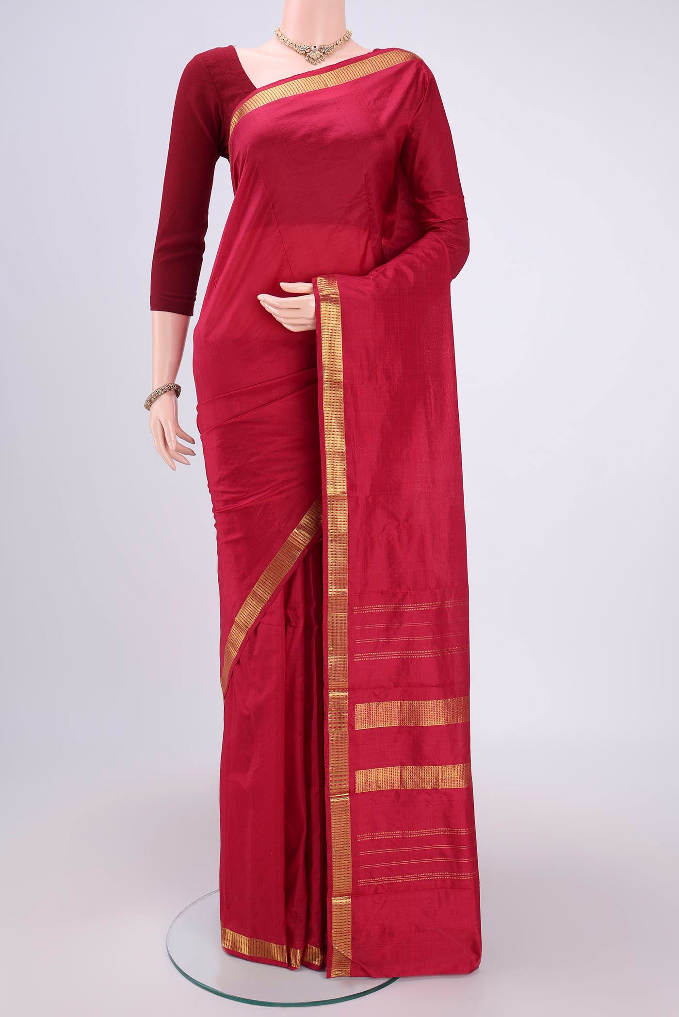 Maroon Kanchipuram Silk Saree with Plain Body and Zari Border.  displayed on a mannequin
