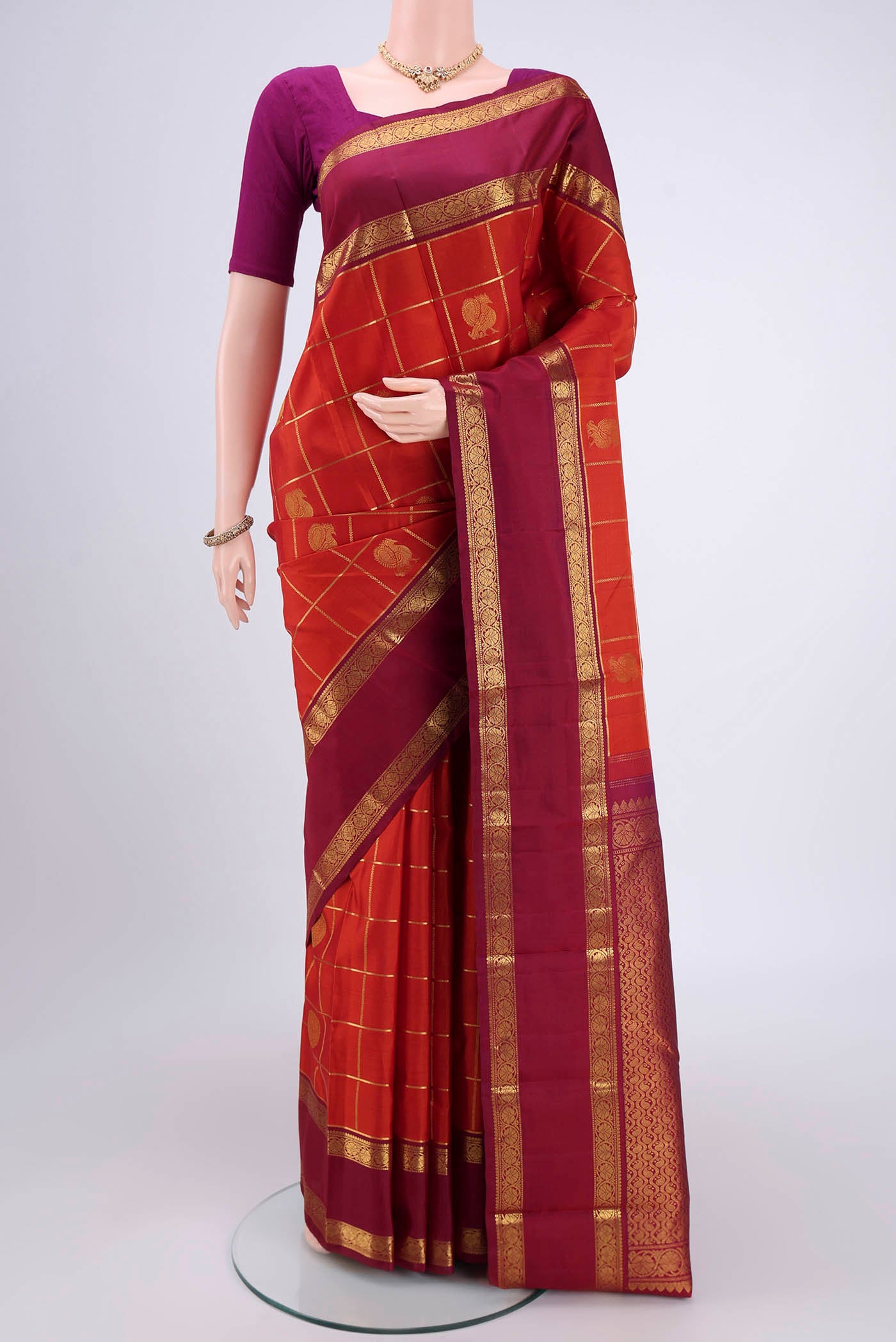 Rust Kanjivaram Silk Saree with Checked design on the body and Zari Border.  displayed on a mannequin