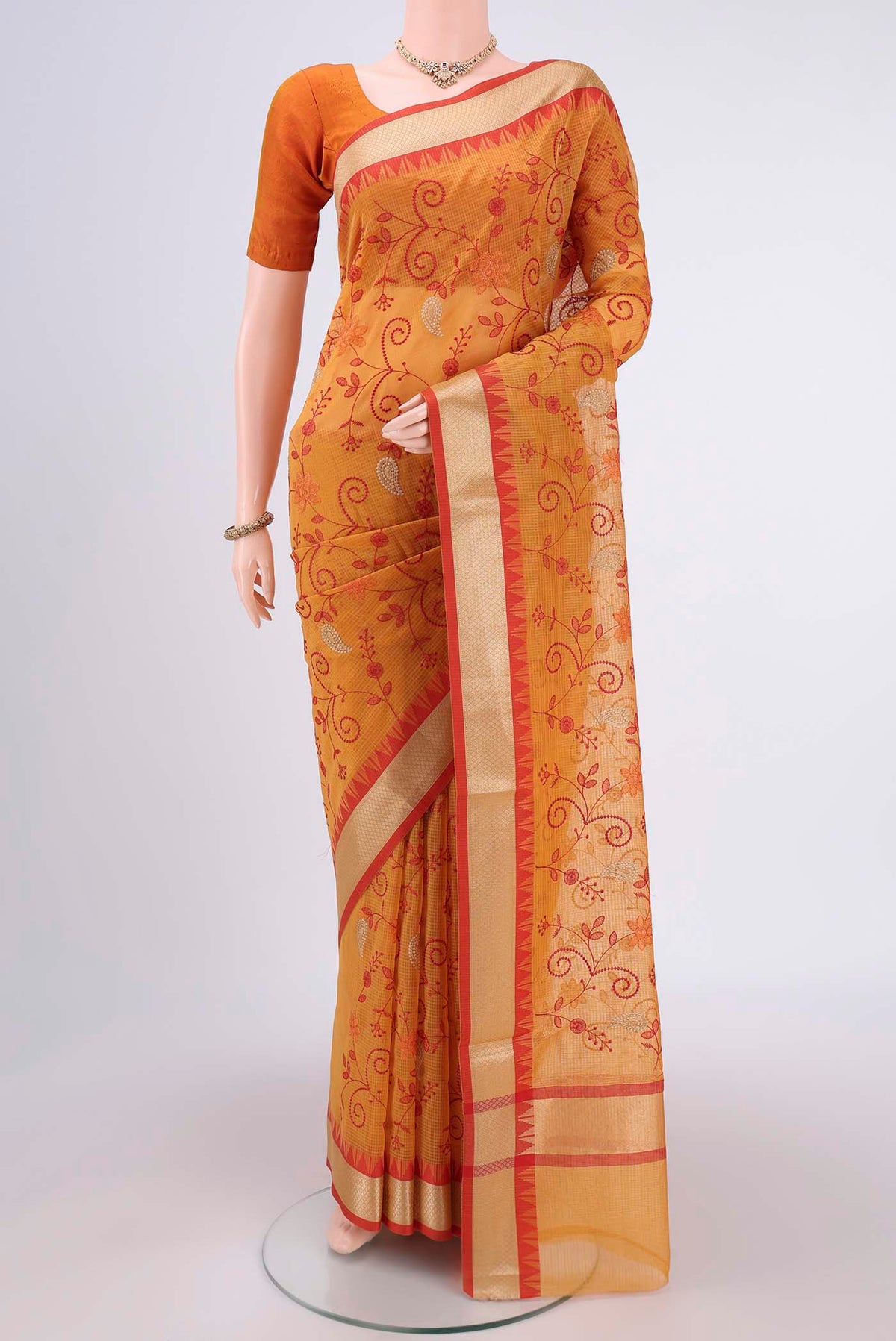 Mustard Kota Silk Saree with Embroidery on the body and Plain Border.  displayed on a mannequin