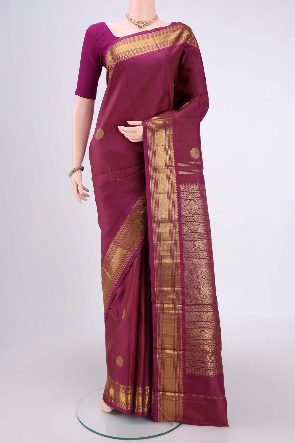 Magenta Kanchipuram Silk Saree with Zari Butta on the body and Zari Border.  displayed on a mannequin