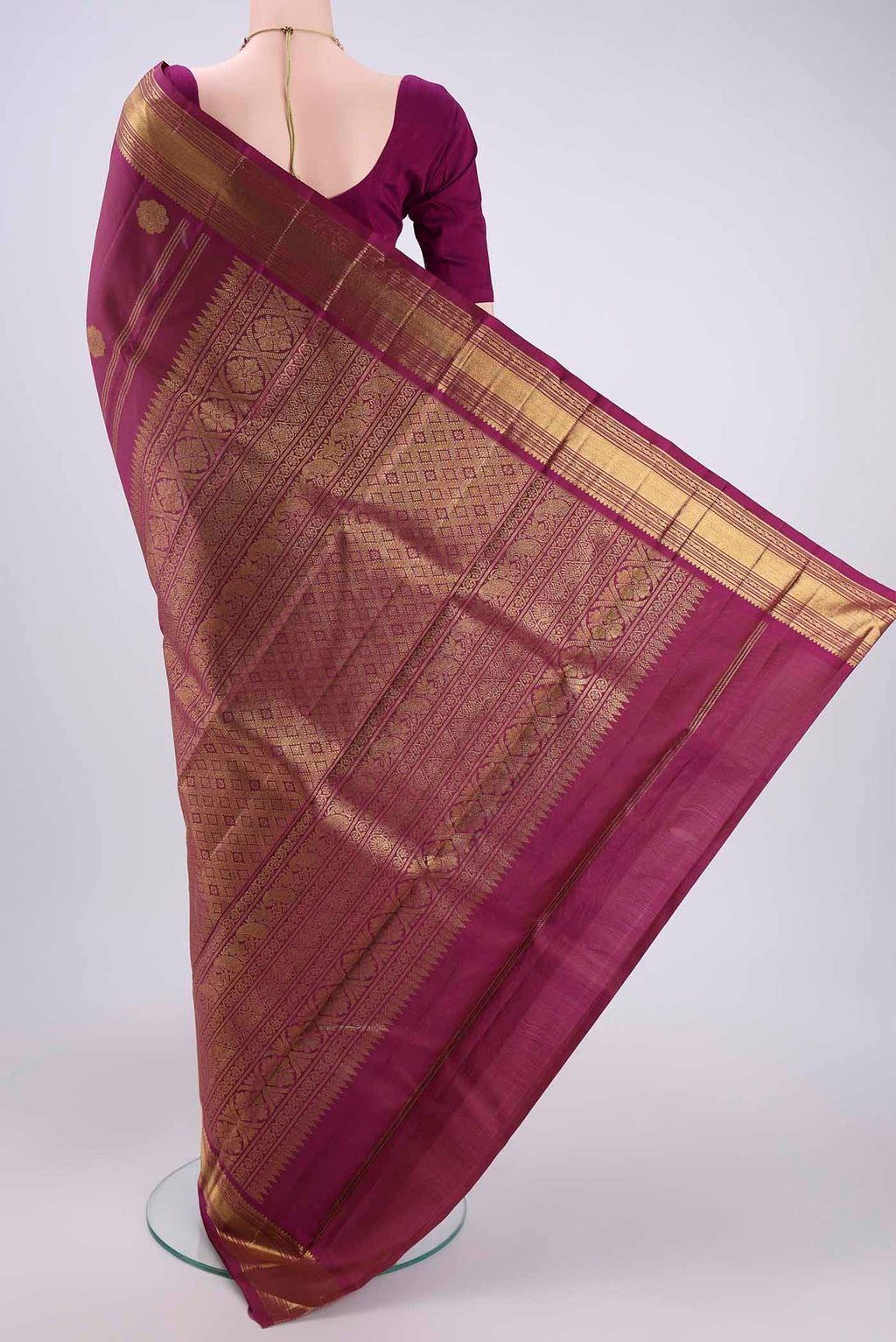 Flat view of Magenta Kanchipuram Silk Saree with Zari Butta on the body and Zari Border. 