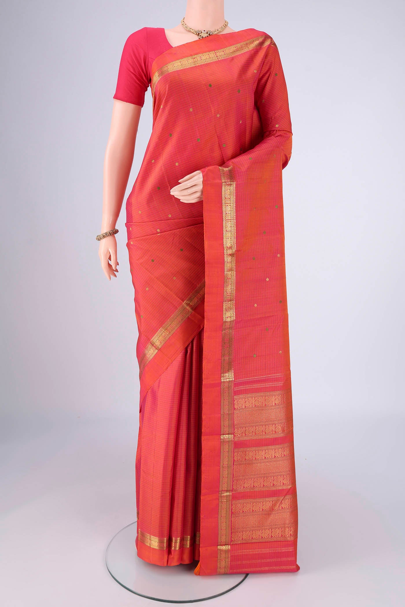 Brick Orange Kanjivaram Silk Saree with Zari And Thread Butta on the body and Zari Border.  displayed on a mannequin