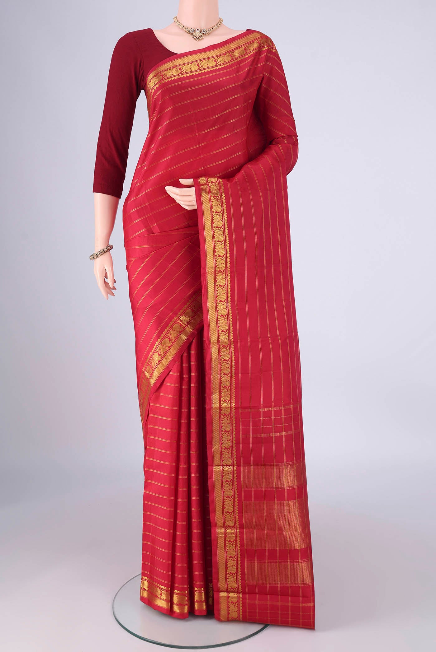 Red Kanchipuram Silk Saree with Stripes on the body and Zari Border.  displayed on a mannequin