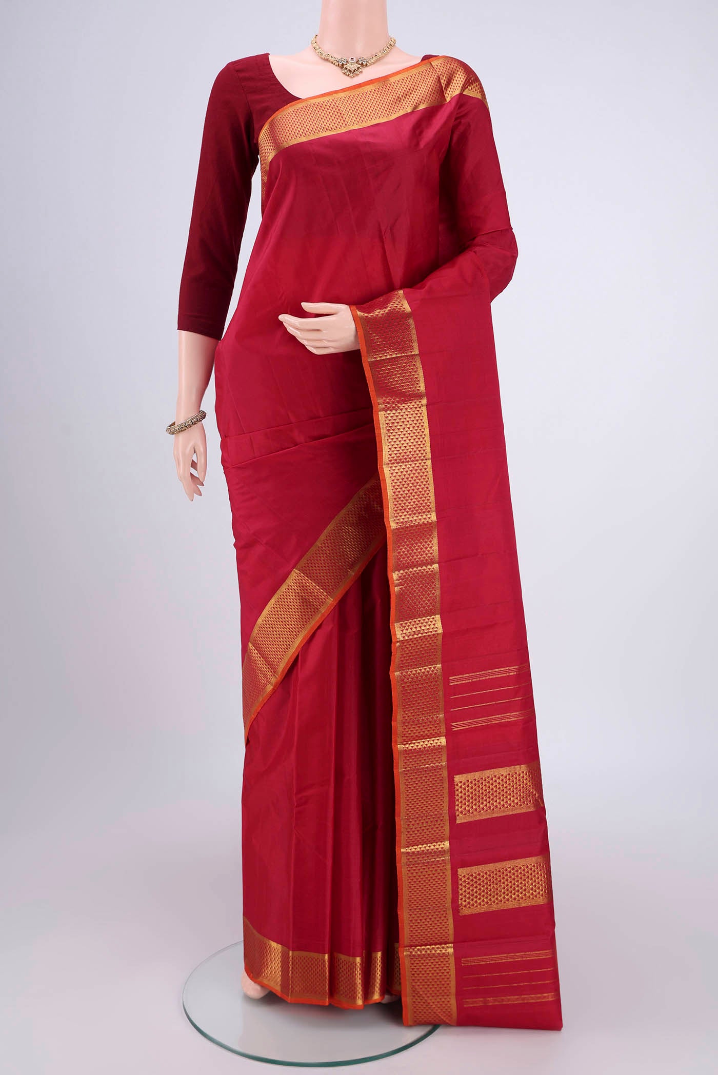 Maroon Kanchipuram Silk Saree with Plain Body and Zari Border.  displayed on a mannequin