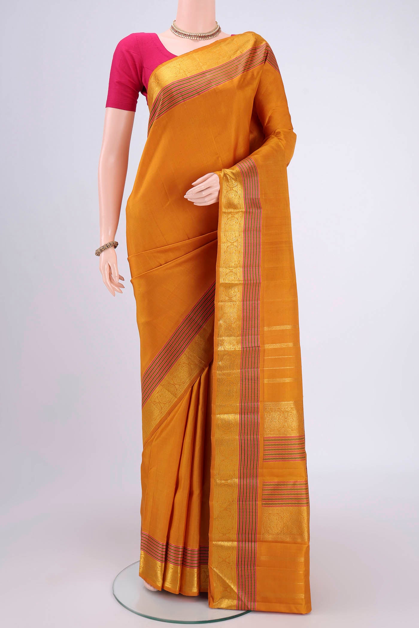 Mustard Kanchipuram Silk Saree with Plain Body and Zari And Thread Border.  displayed on a mannequin