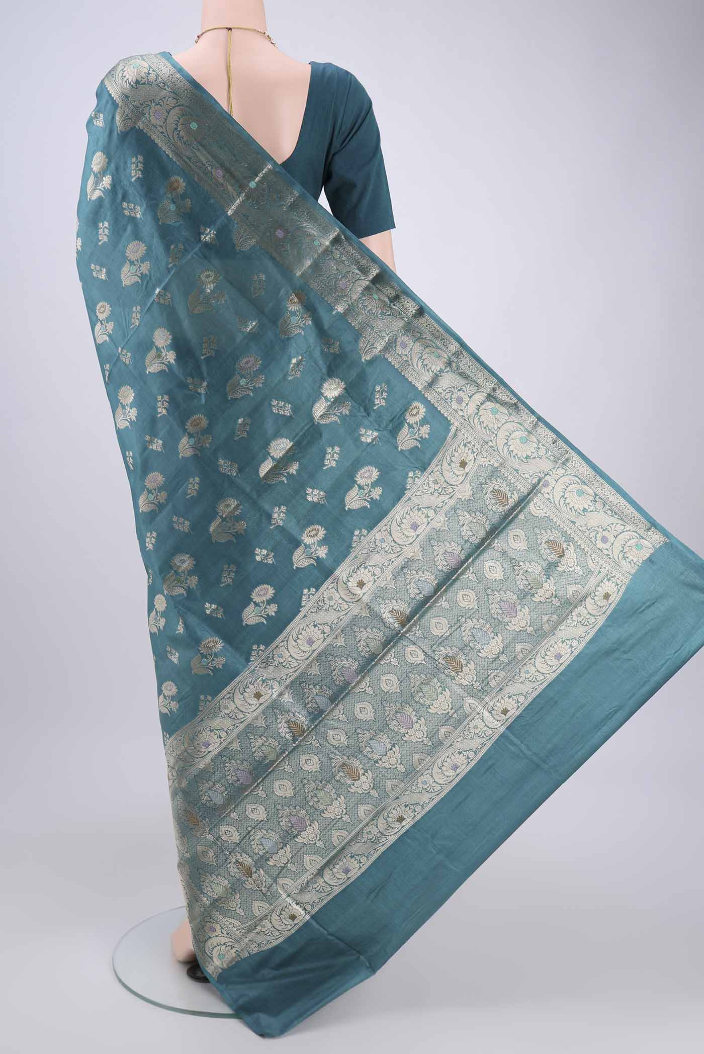 Flat view of Turquoise Banarasi Tussar Silk Saree with Zari And Thread Butta on the body and Zari And Thread Border. 
