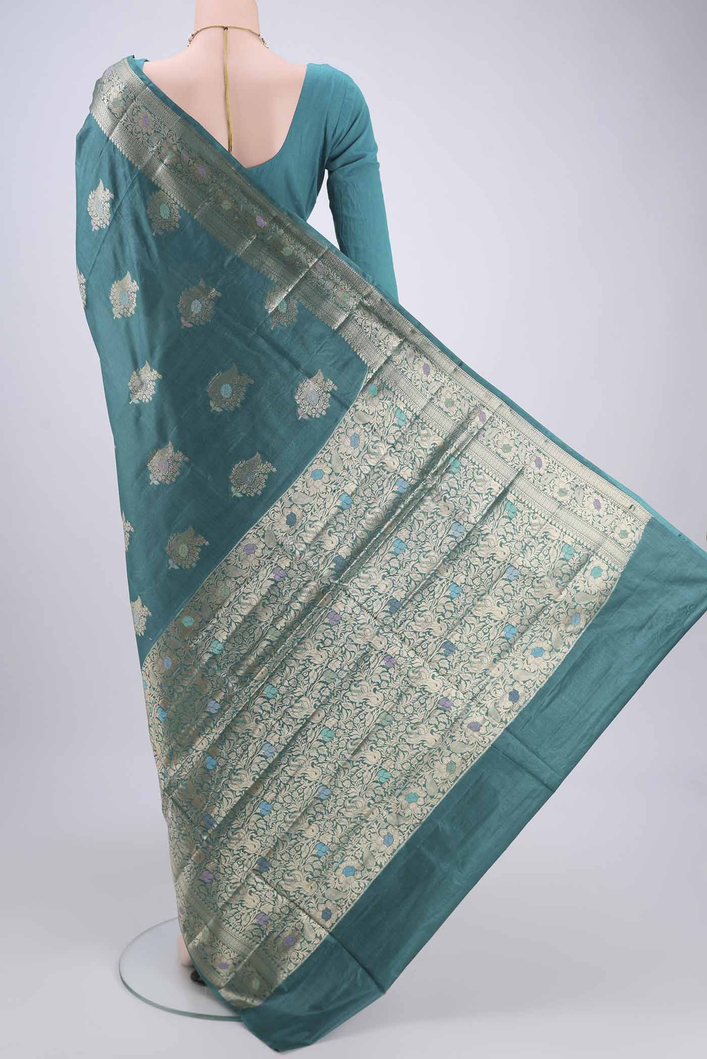 Flat view of Turquoise Banarasi Tussar Silk Saree with Zari And Thread Butta on the body and Zari And Thread Border. 