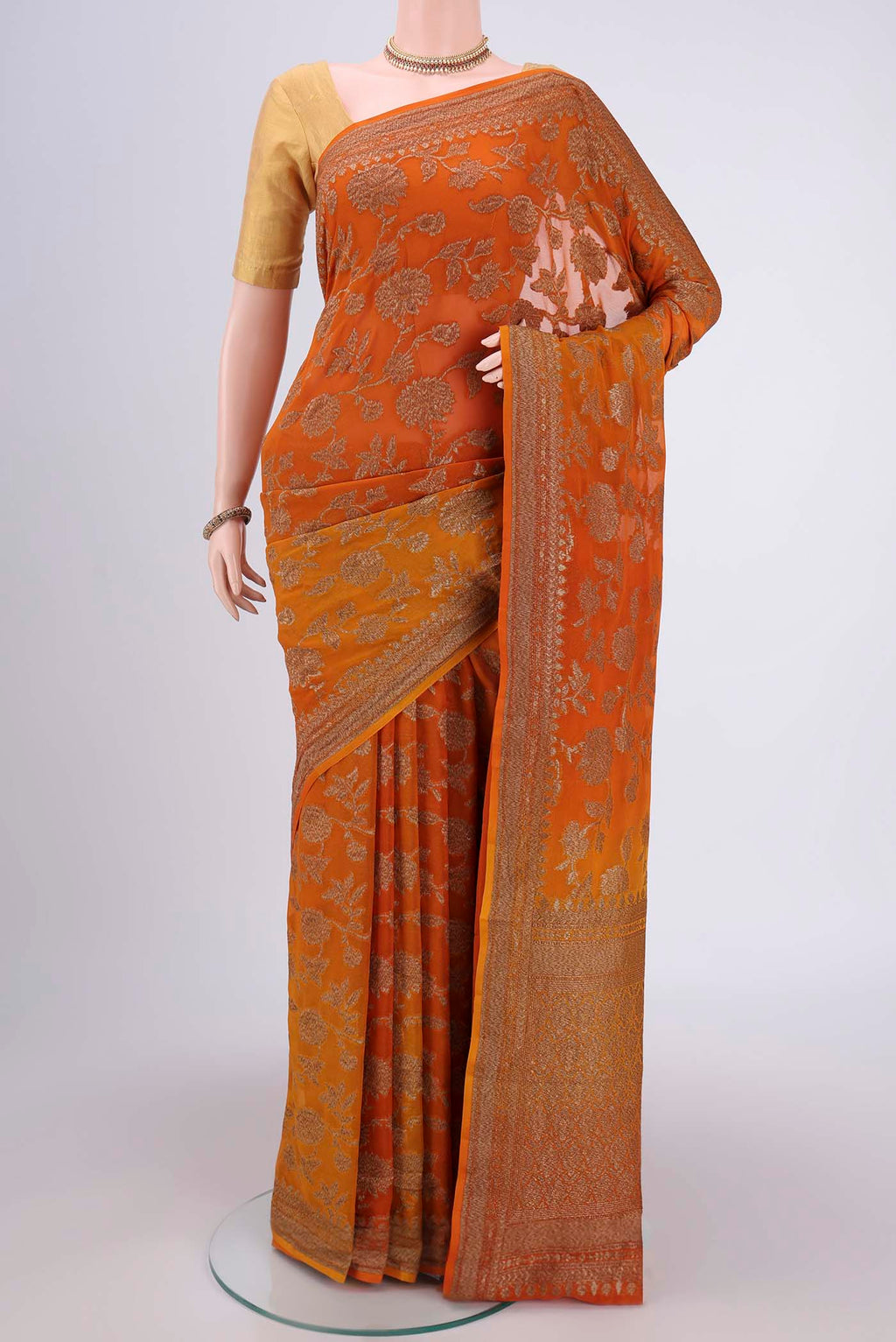 Rust Banarasi Georgette Saree with Zari Brocade on the body and Zari Border.  displayed on a mannequin