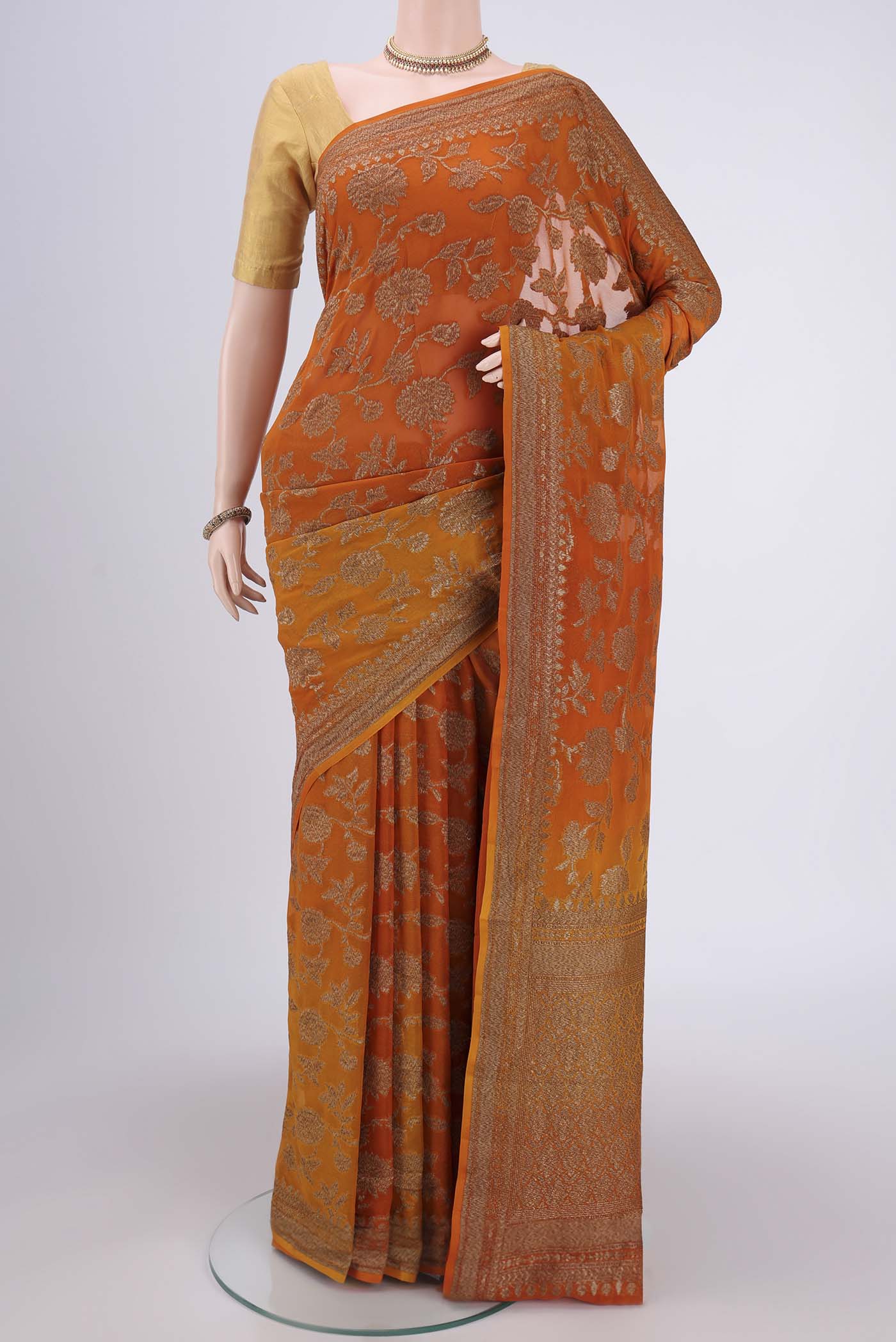 Rust Banarasi Georgette Saree with Zari Brocade on the body and Zari Border.  displayed on a mannequin