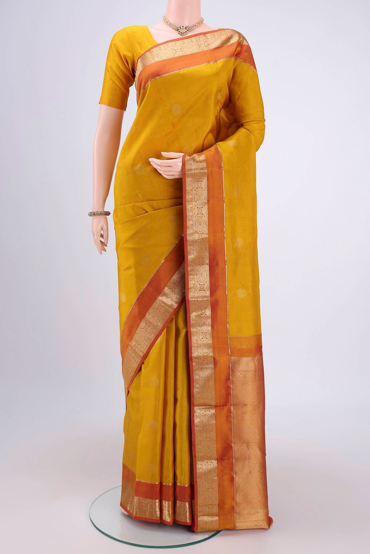 Yellow Kanchipuram Silk Saree with Zari Butta on the body and Zari Border.  displayed on a mannequin