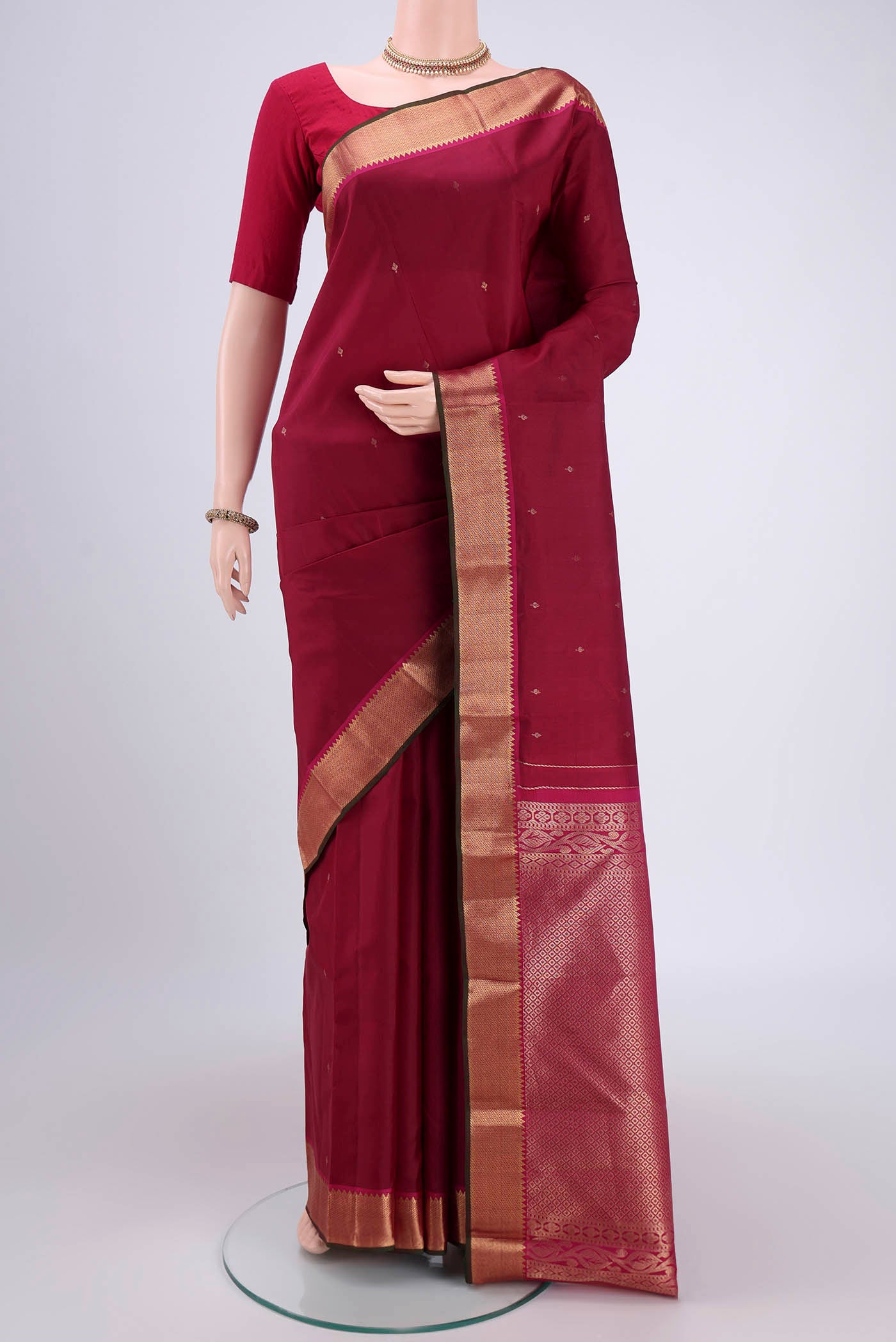 Rust Kanjivaram Silk Saree with Zari Butta on the body and Zari Border.  displayed on a mannequin