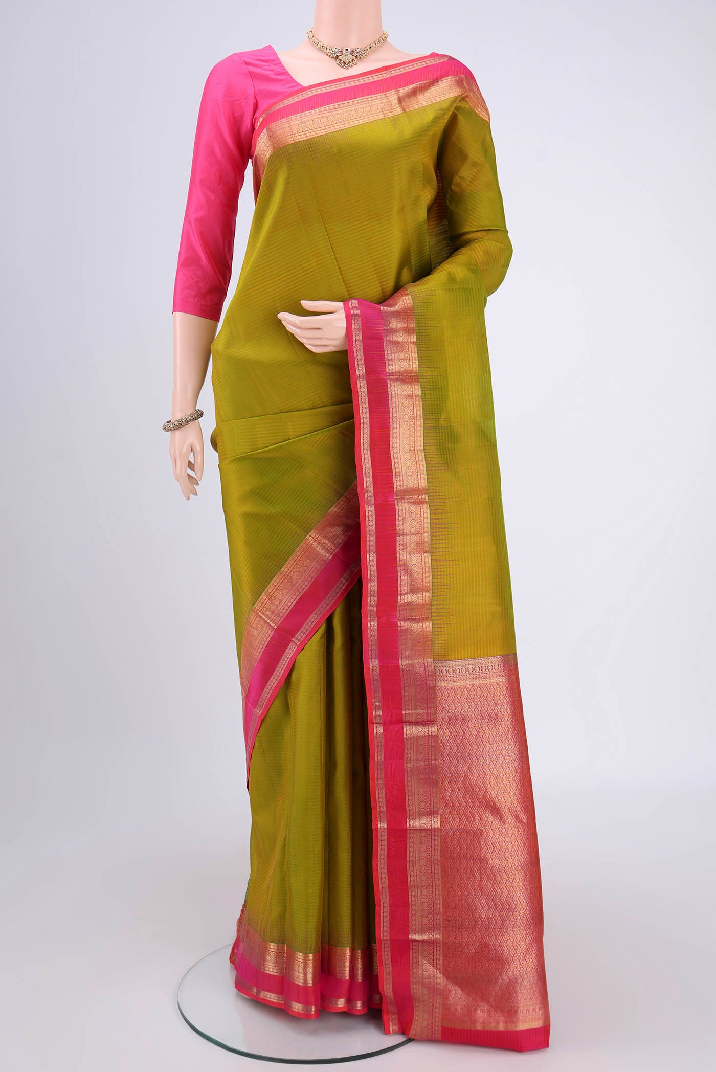 Green Kanchipuram Silk Saree with Zari Butta on the body and Zari Border.  displayed on a mannequin