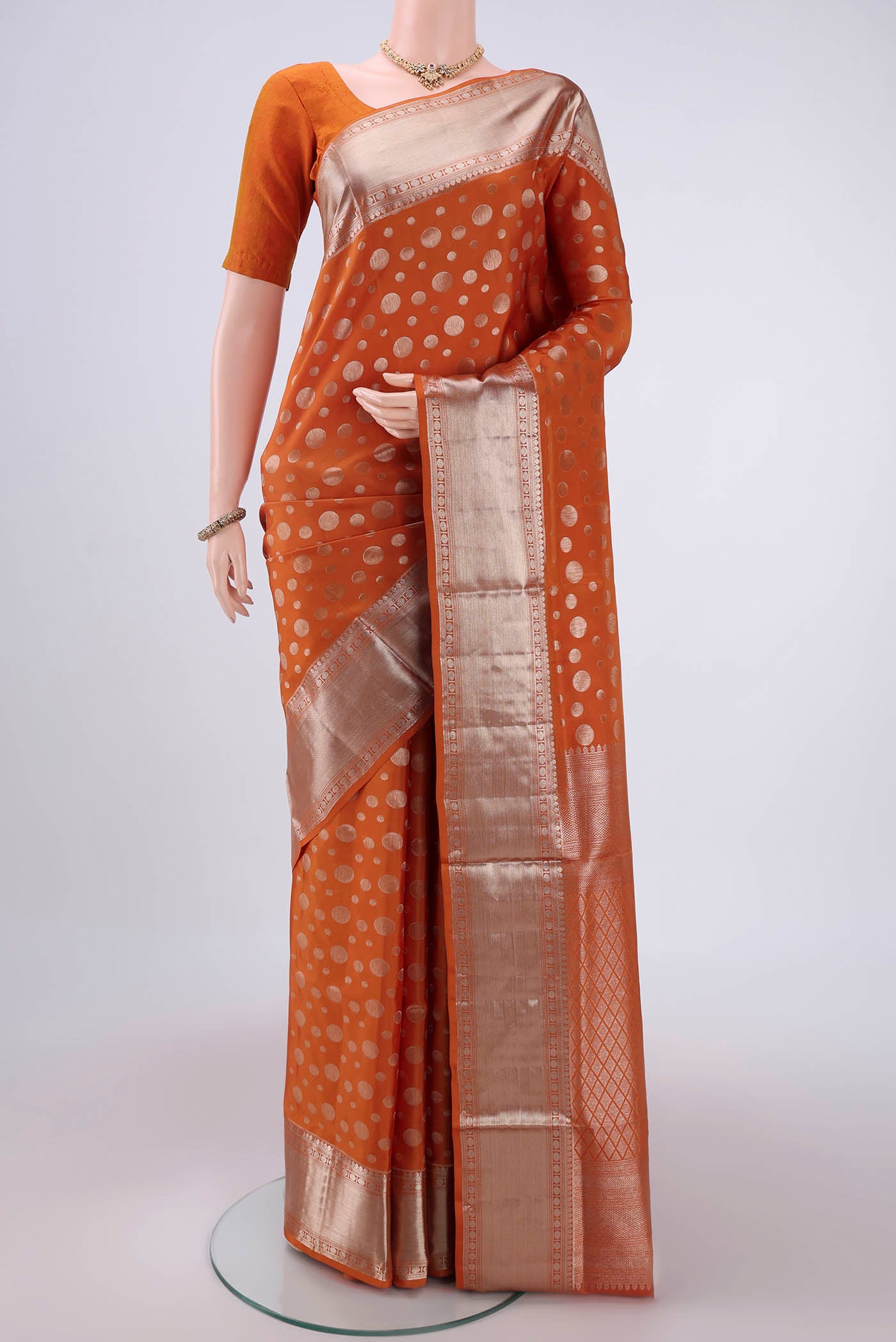 Rust Soft Silk Saree with Polka Dots on the body and Zari Border.  displayed on a mannequin