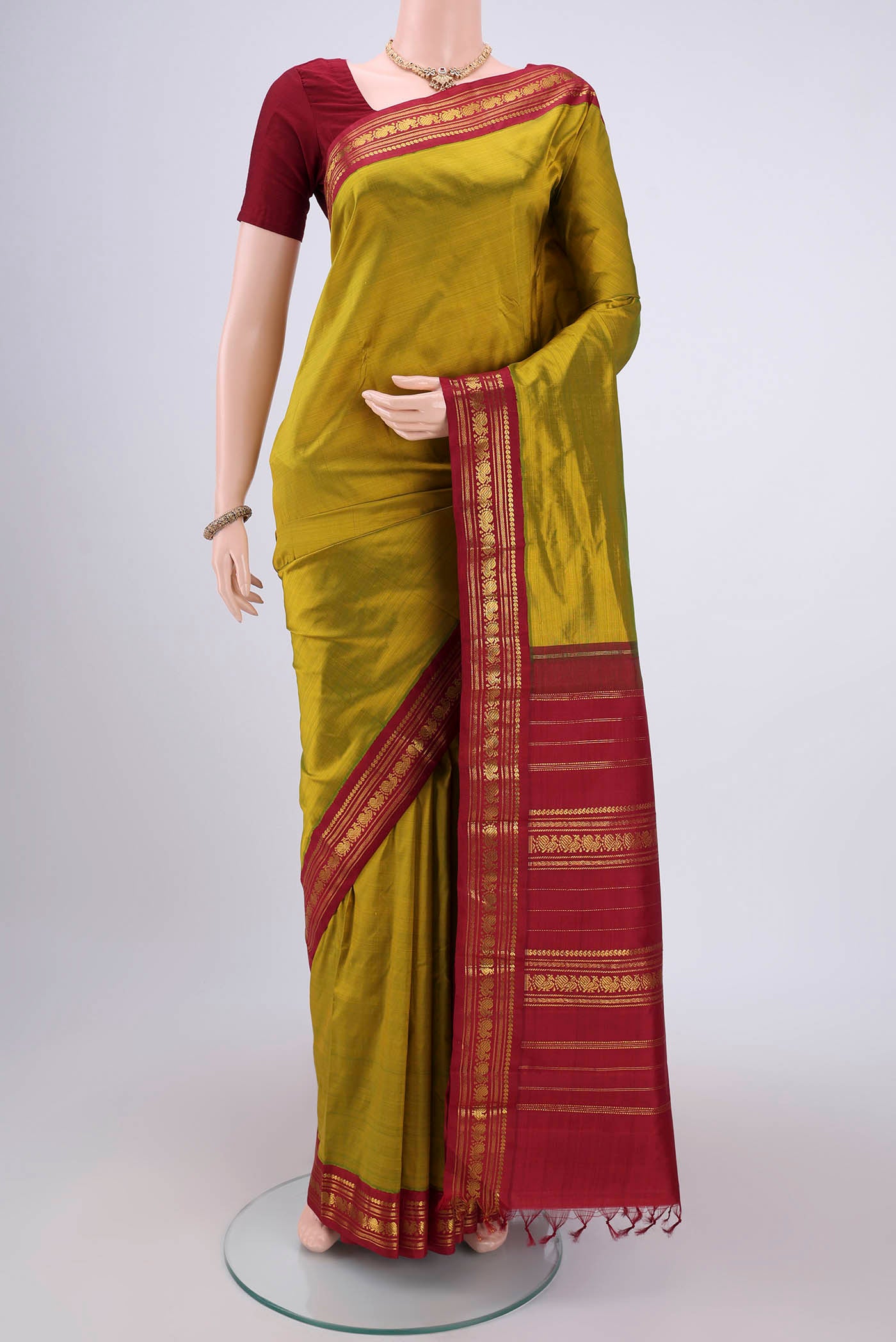 Mehandi Green Kanchipuram Saree with Plain Body and Zari Border.  displayed on a mannequin