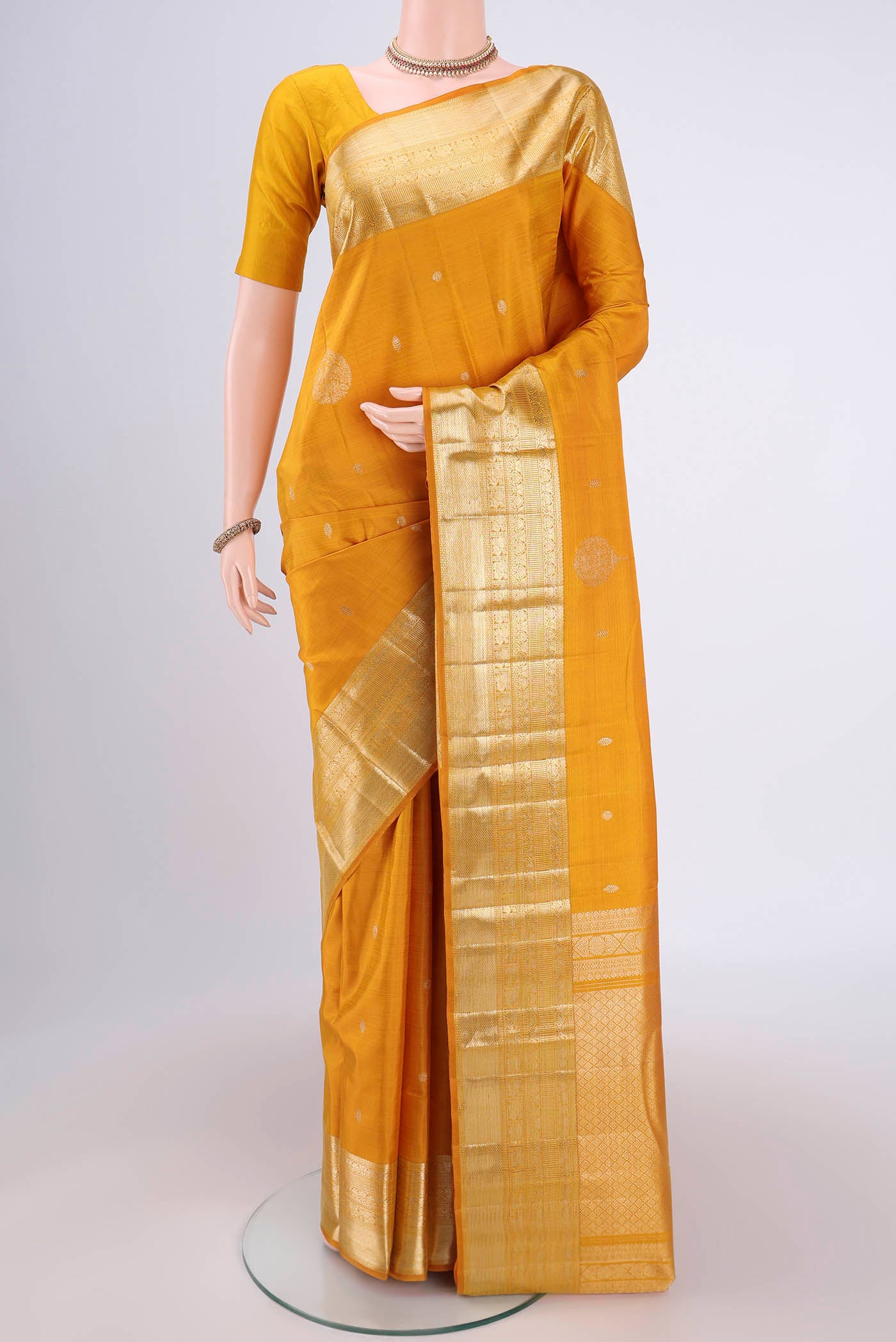 Yellow Kanjivaram Silk Saree with Zari Butta on the body and Zari Border.  displayed on a mannequin