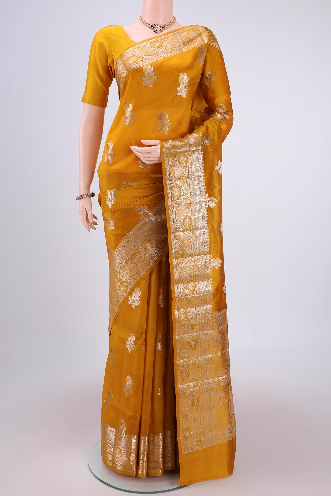 Mustard Banarasi Raw Silk Saree with Zari Butta on the body and Zari Border.  displayed on a mannequin